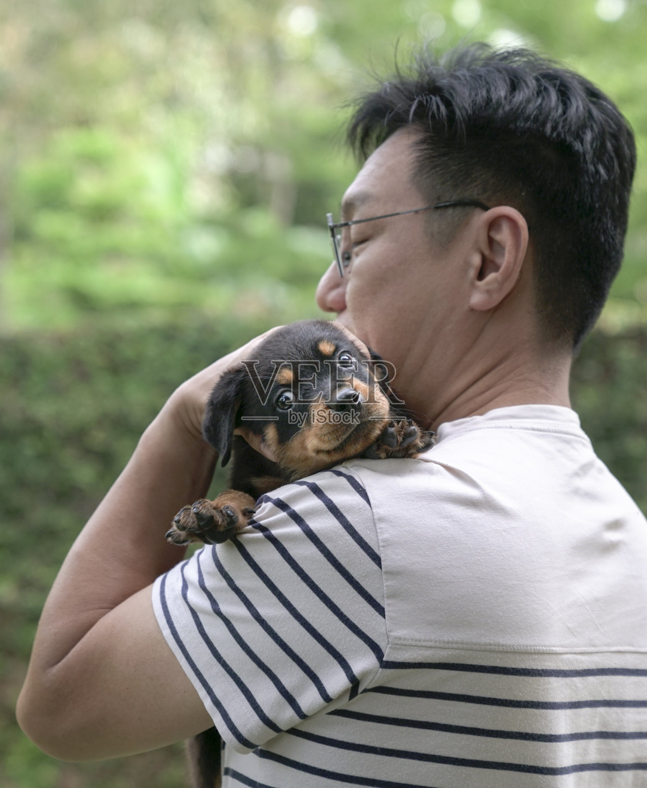 一个成年男子把小狗抱在肩上。副本的空间。照片摄影图片