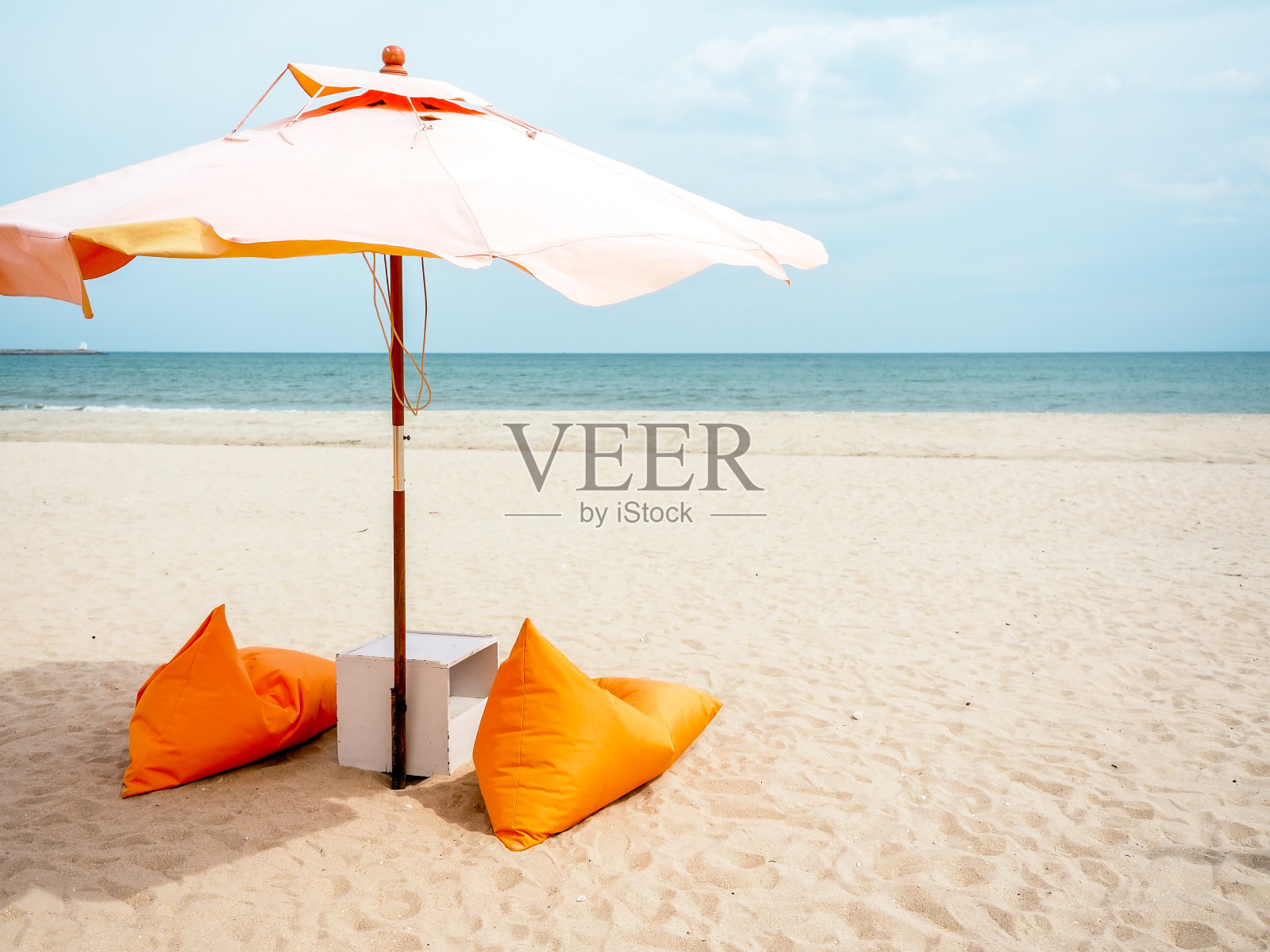 沙滩上的橙色沙滩伞和豆袋椅。照片摄影图片