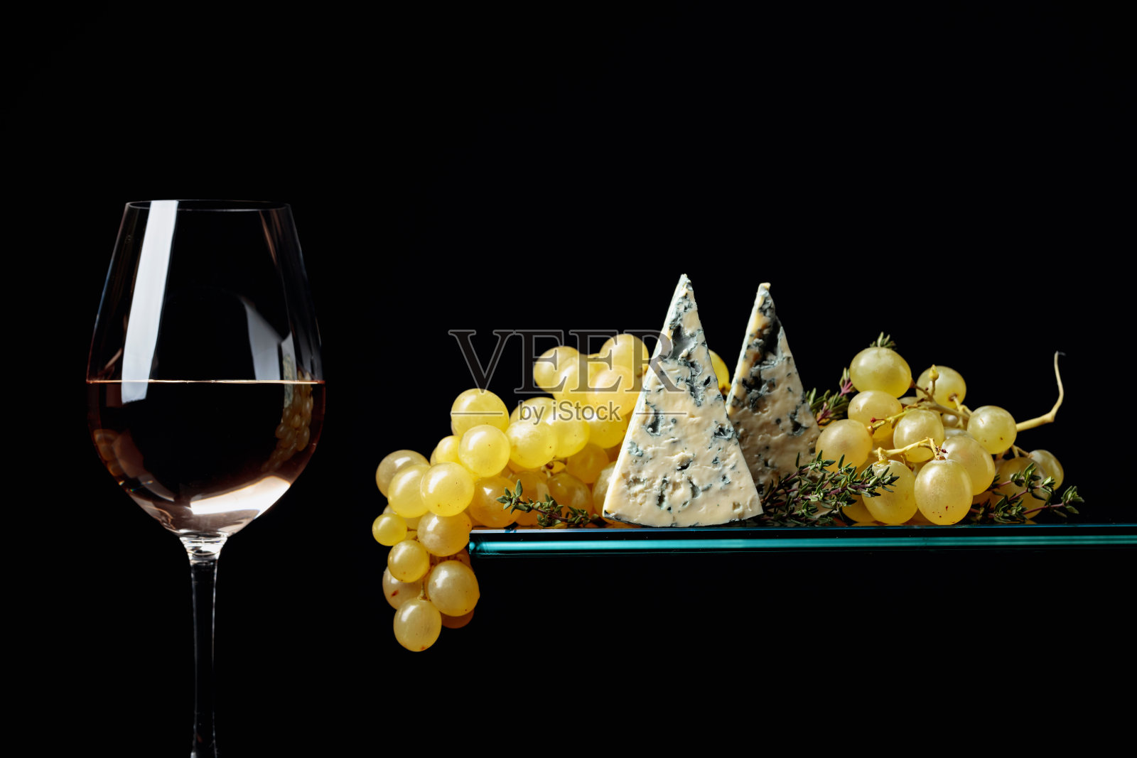 一杯白葡萄酒配零食。葡萄配蓝奶酪和百里香。照片摄影图片