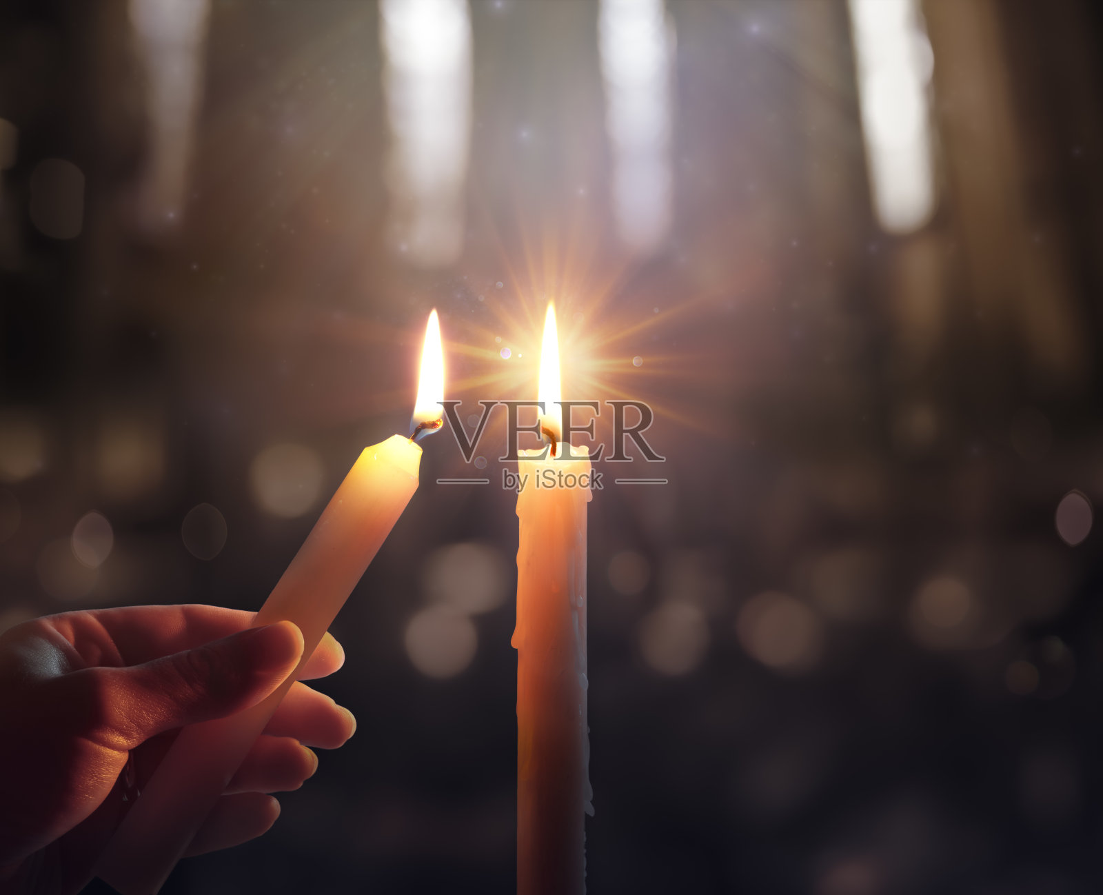 散焦希望概念-手点燃蜡烛与闪耀的火焰和模糊的灯光照片摄影图片