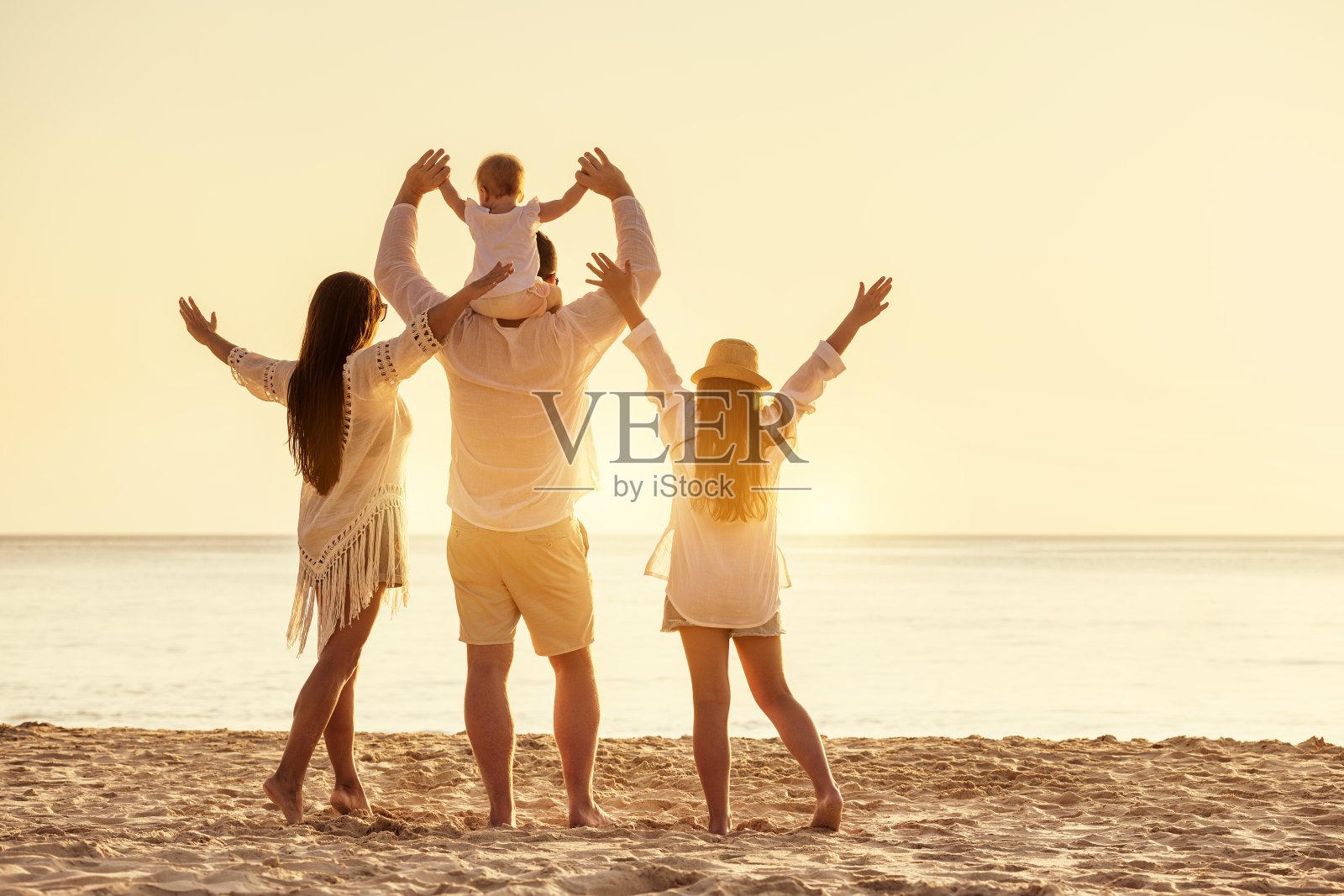 四口之家在日落海滩上举着手照片摄影图片