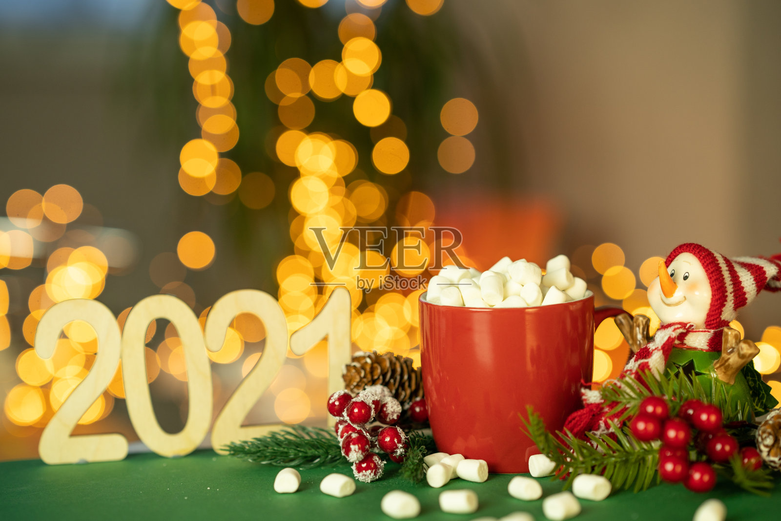 一个放着可可和棉花糖的红杯子，旁边放着一个雪人。用明亮的花环装饰的圣诞节装饰品。选择性聚焦，浅景深，背景。2021.照片摄影图片