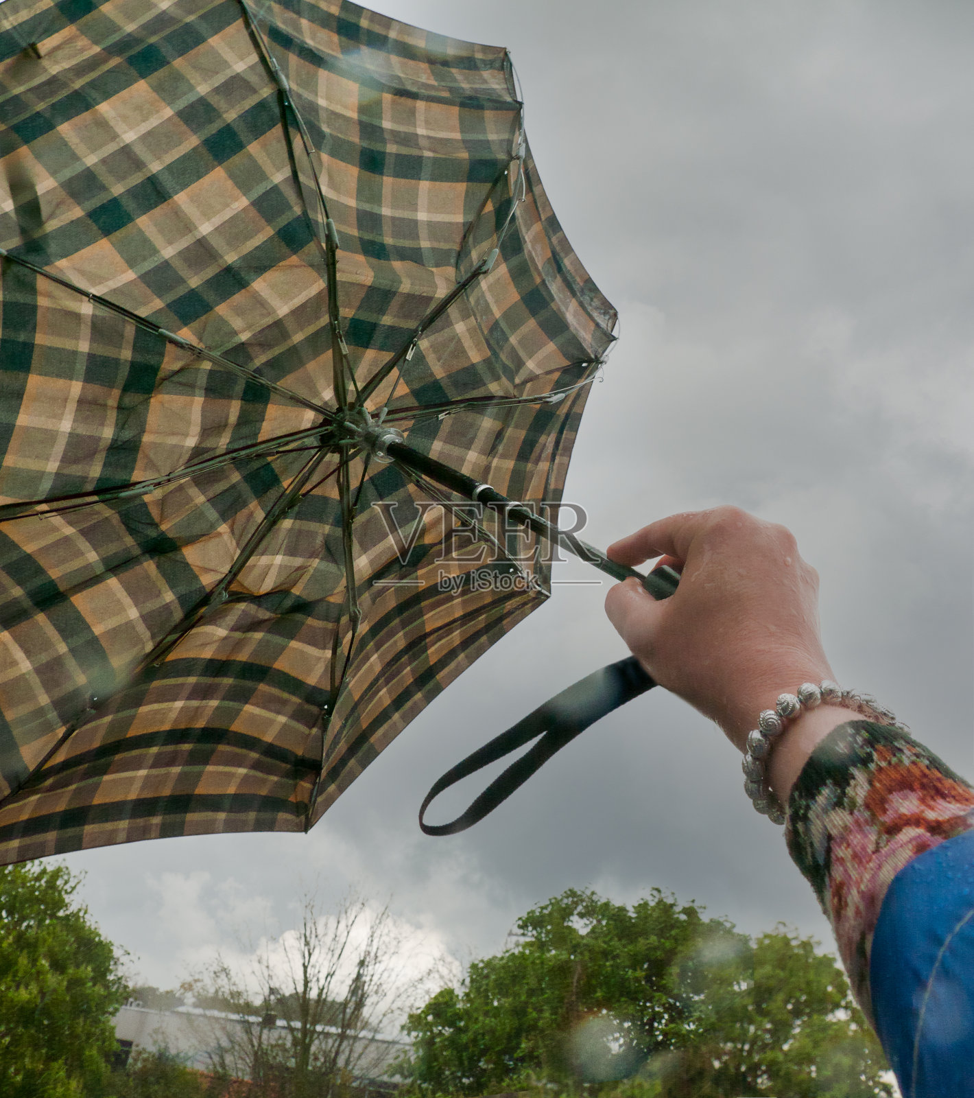 一个女人在暴风雨中抓着雨伞照片摄影图片