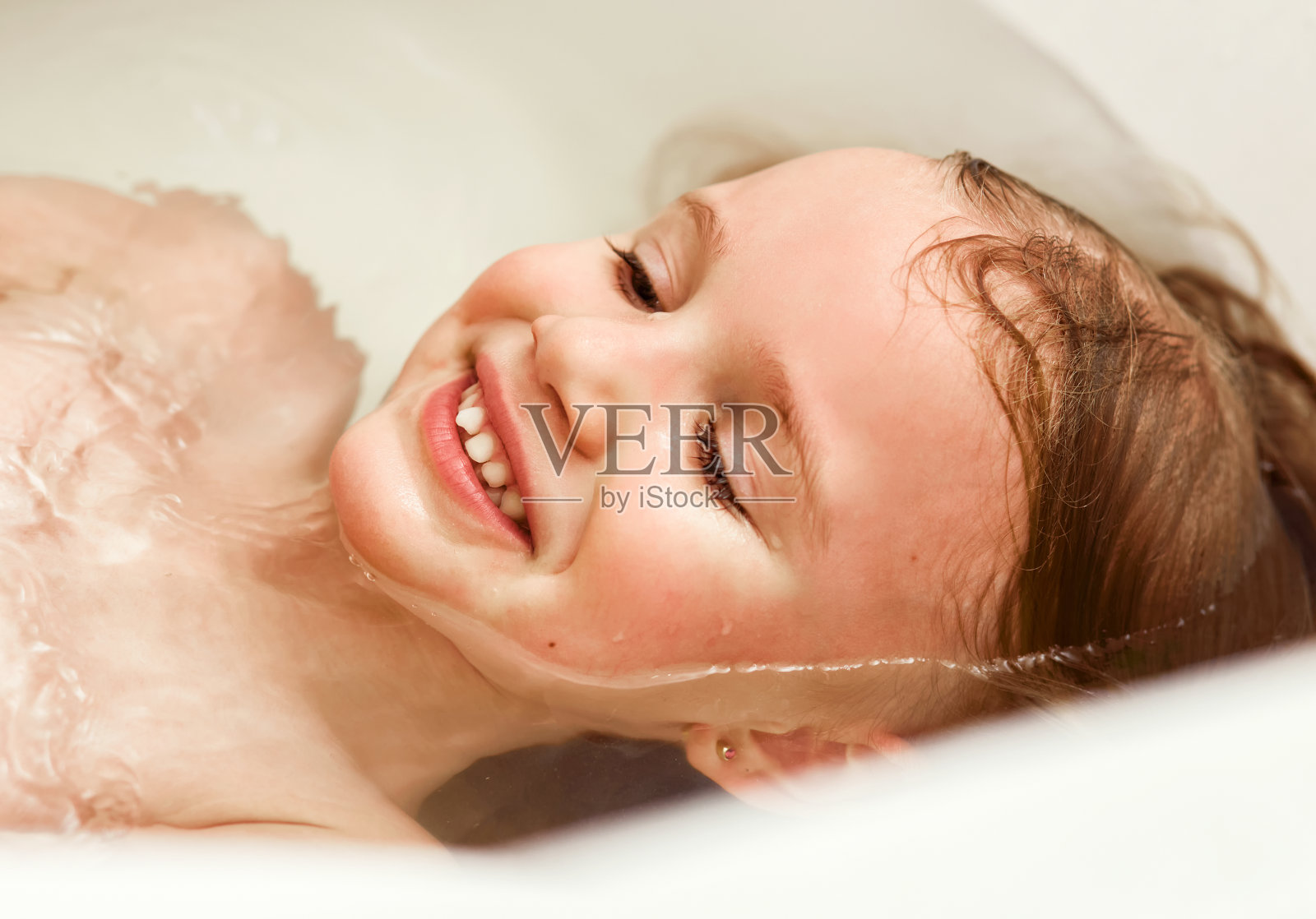 俯视小女孩躺在浴缸里照片摄影图片