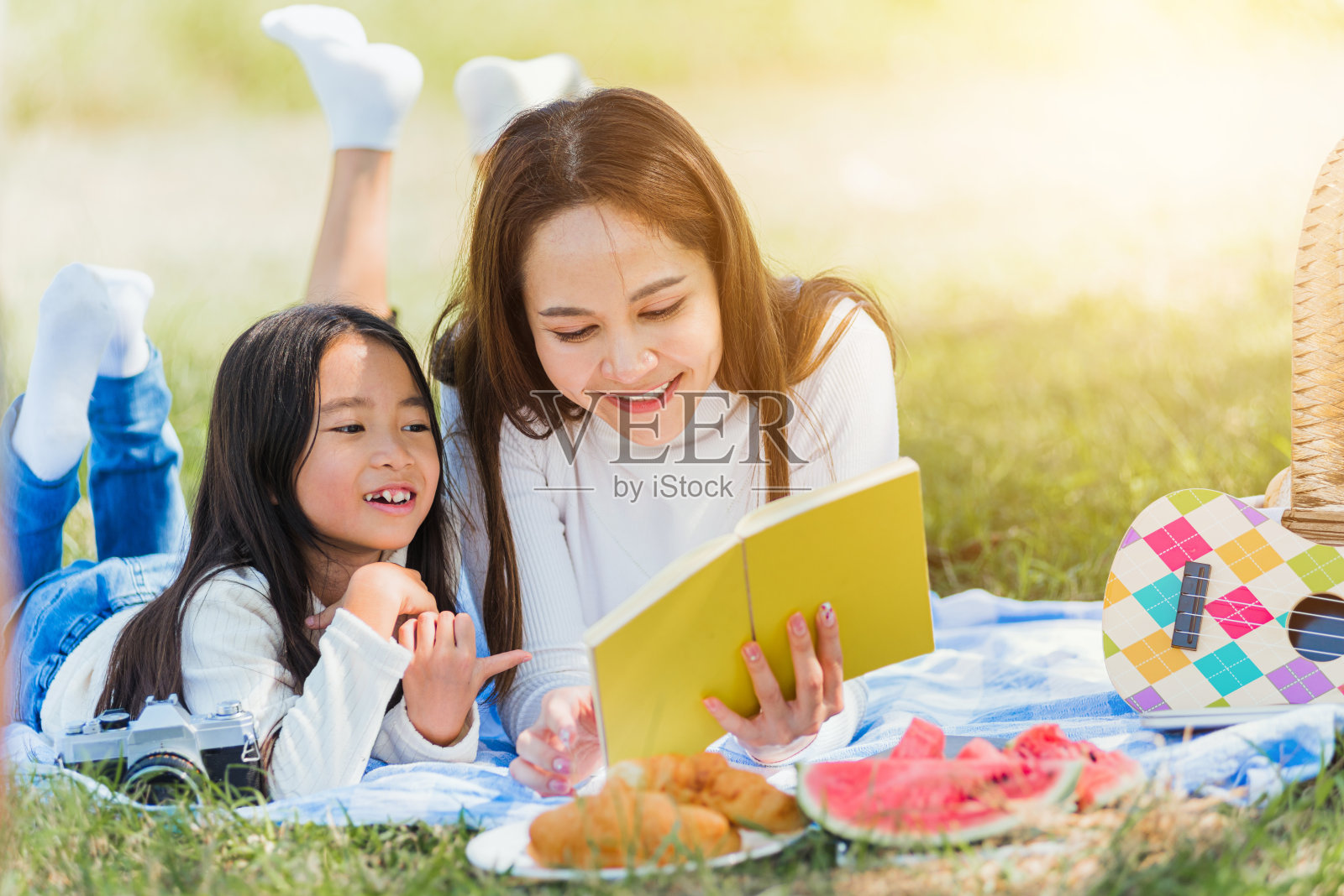 快乐的家庭有乐趣，享受户外躺在野餐毯上看书照片摄影图片