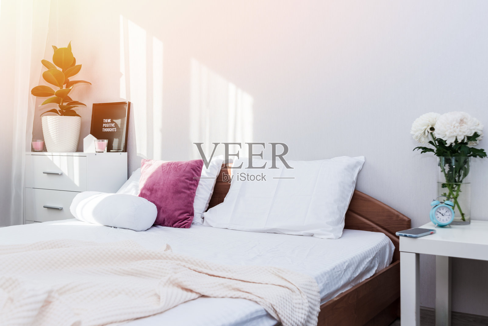 生活化的卧室室内，在自然的晨光下，床上有粉色和白色的枕头。照片摄影图片