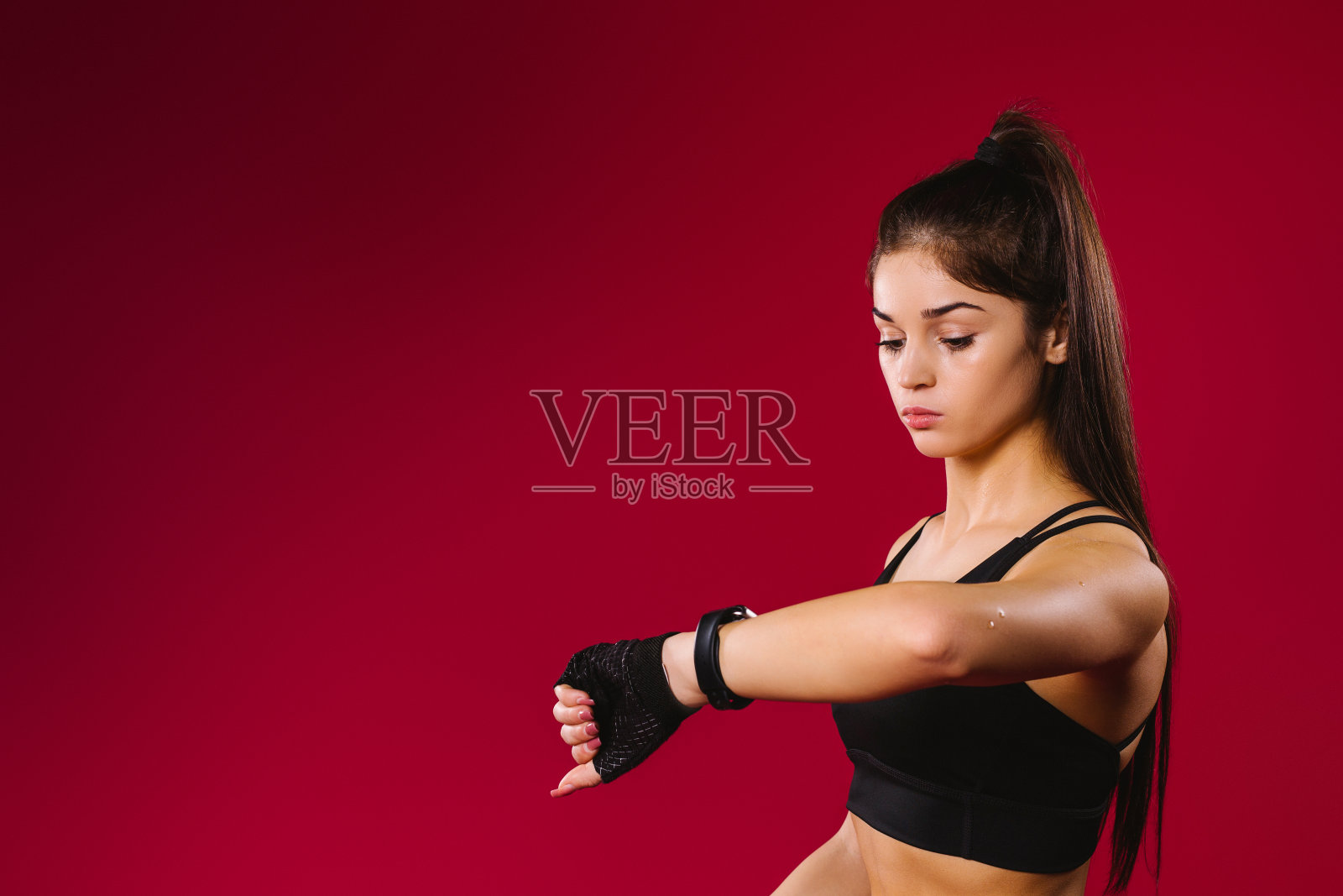 女运动员训练后在健身智能手表应用中查看自己的工作。智能手表，红色背景和侧面空间。照片摄影图片