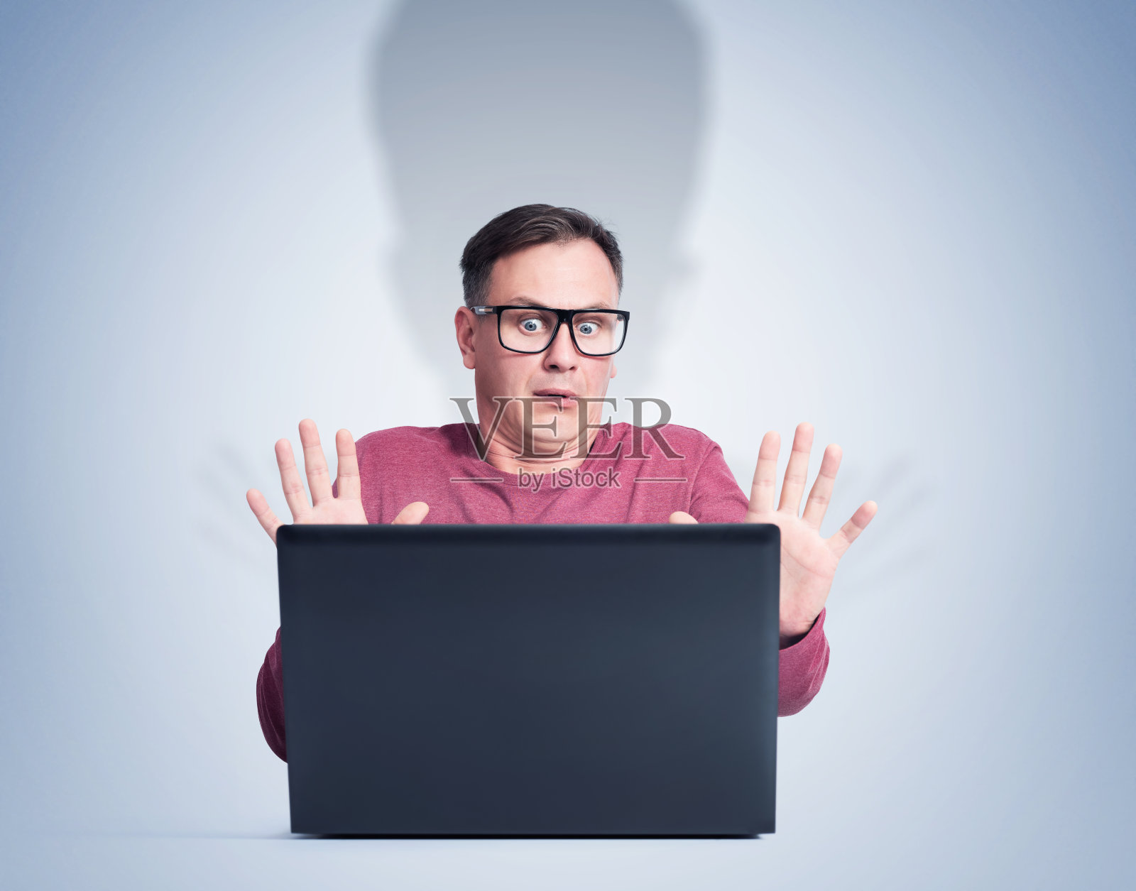 一个戴着眼镜坐在电脑前的害怕的男人。恐惧情绪的概念照片摄影图片