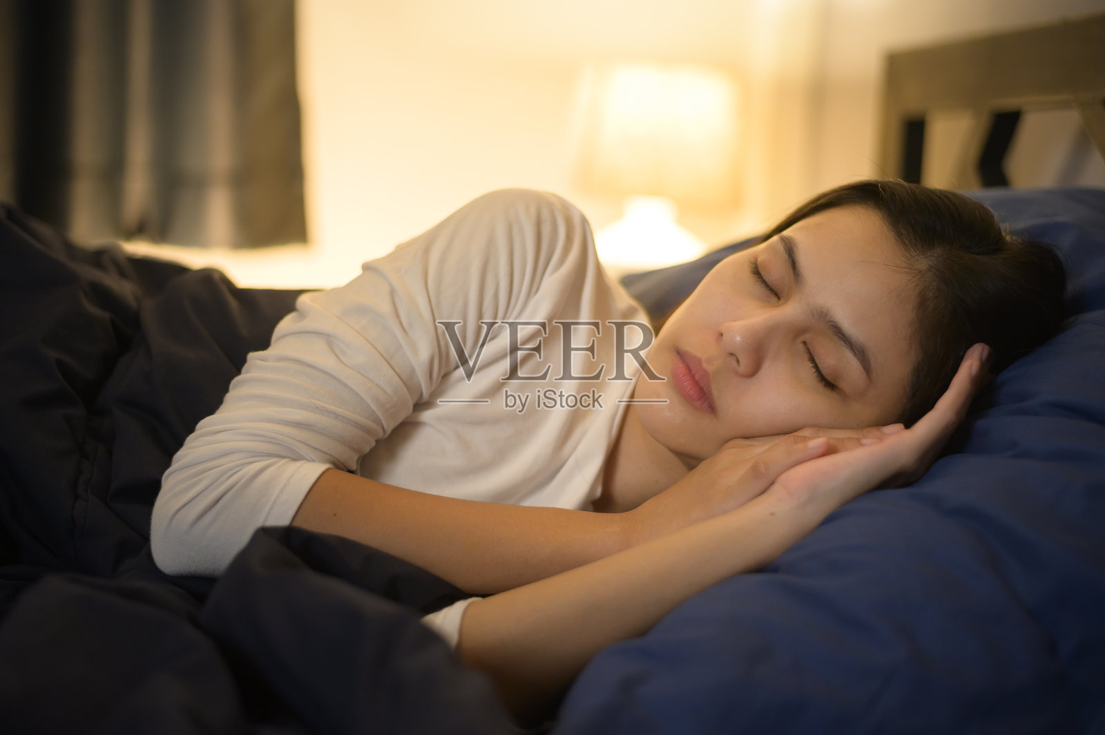 一个年轻女子在她的卧室里睡觉，健康和家庭安全的概念。照片摄影图片