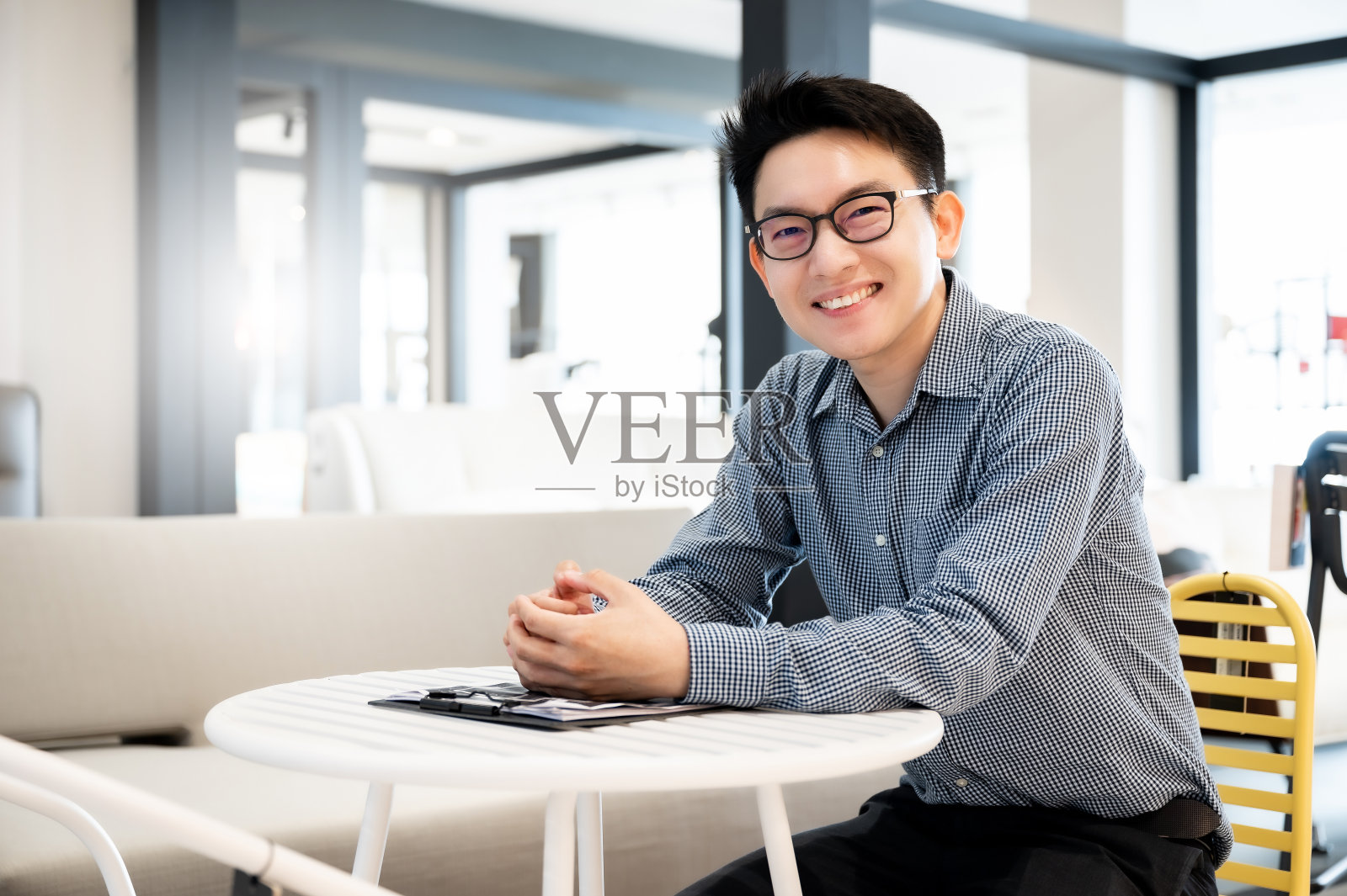 一个快乐的年轻人坐在现代化的办公室里，微笑着看着镜头照片摄影图片