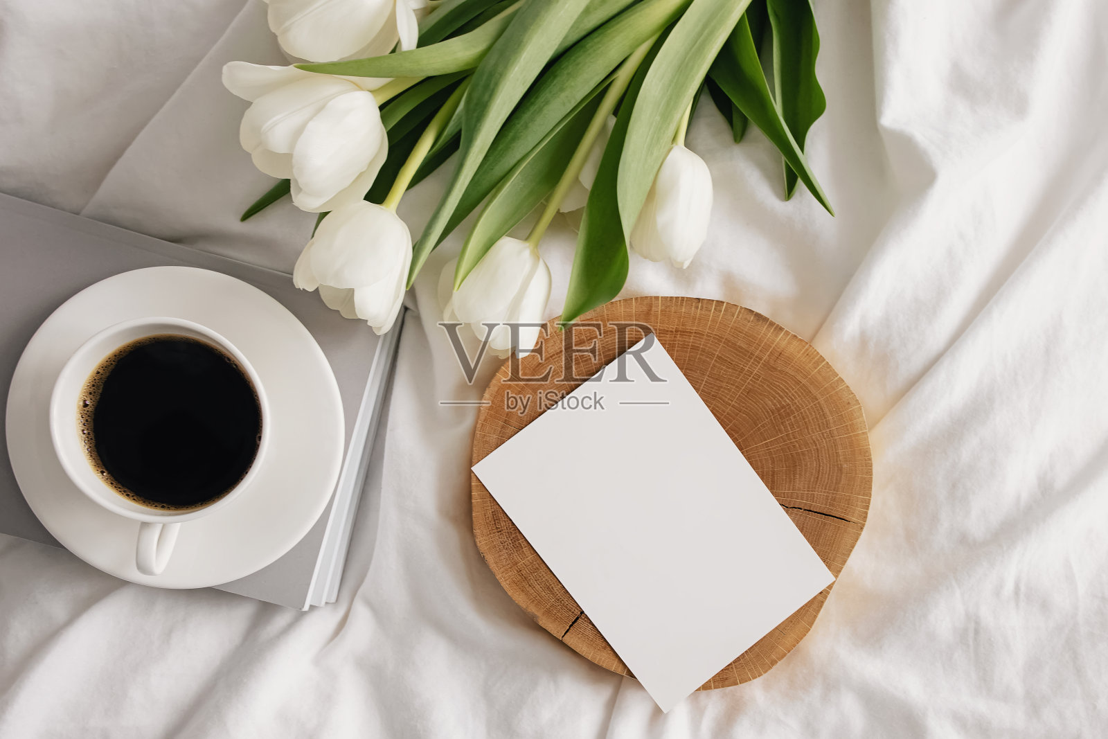 咖啡，白色郁金香和床上的空纸卡照片摄影图片