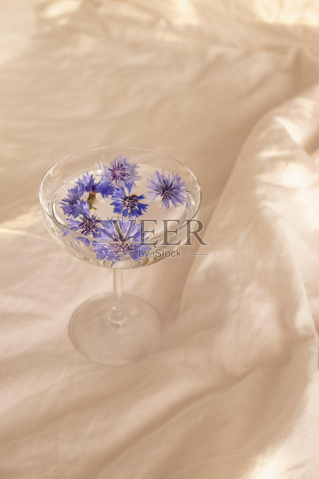蓝色的花头放在杯子里，床上有清水照片摄影图片