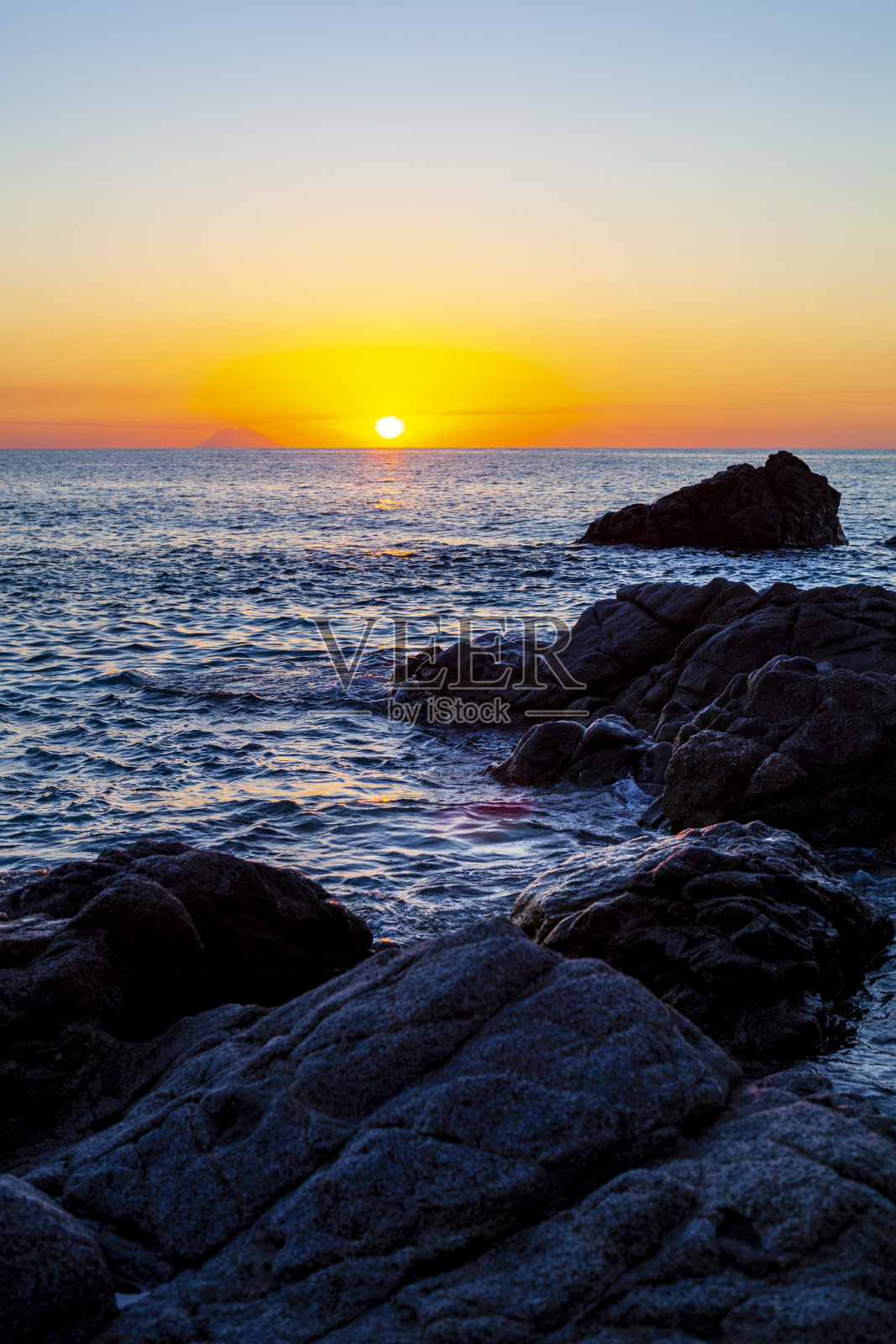 岩石海岸上的日落。照片摄影图片