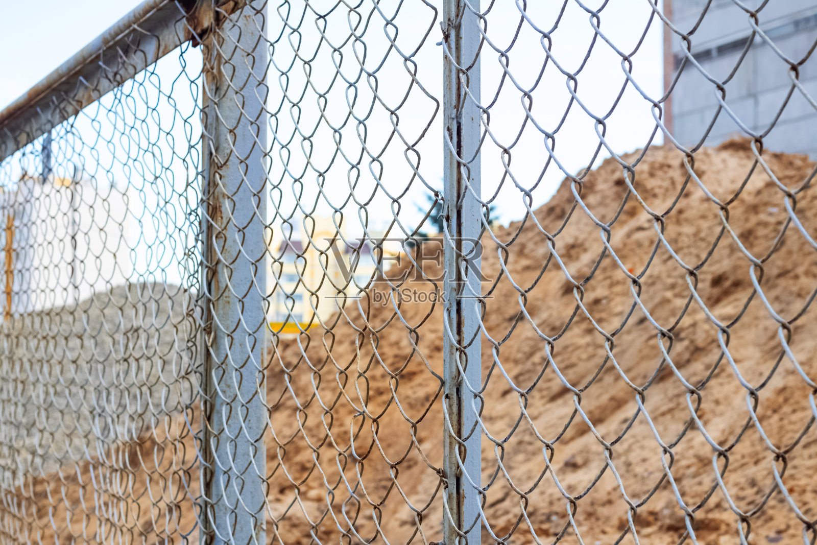 建筑工地金属栅栏后的砂石堆照片摄影图片