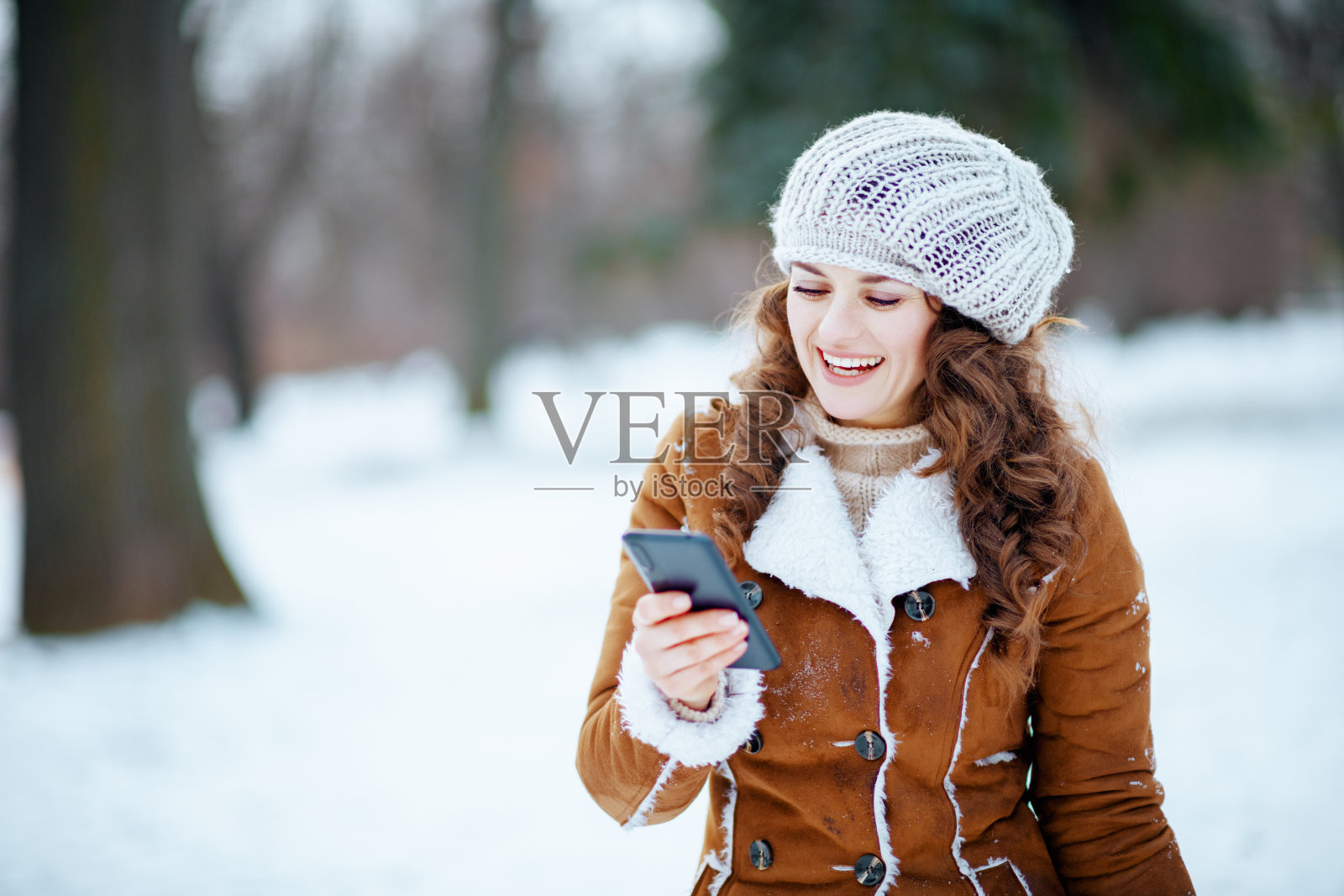 女人在城市公园的冬天使用手机应用程序照片摄影图片