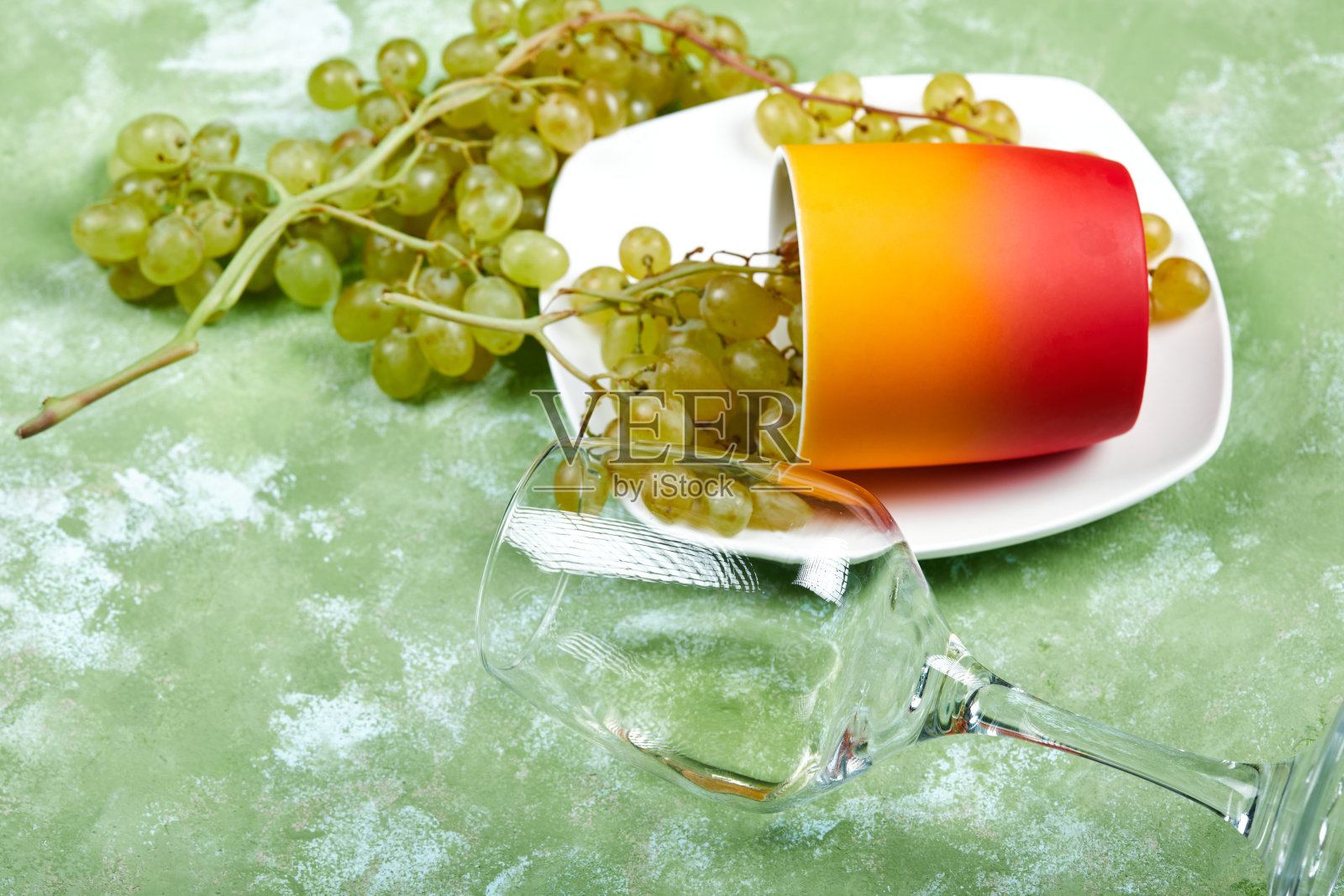 一串白葡萄，一个杯子，一个空酒杯在绿色的背景照片摄影图片