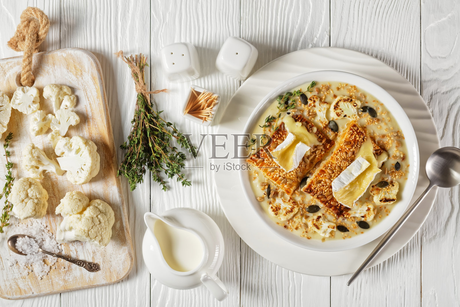 奶油素食花椰菜汤，上面放着烤面包和融化的卡门贝尔奶酪，放在木桌上，上面是水平视图，特写，平铺，法式菜肴照片摄影图片