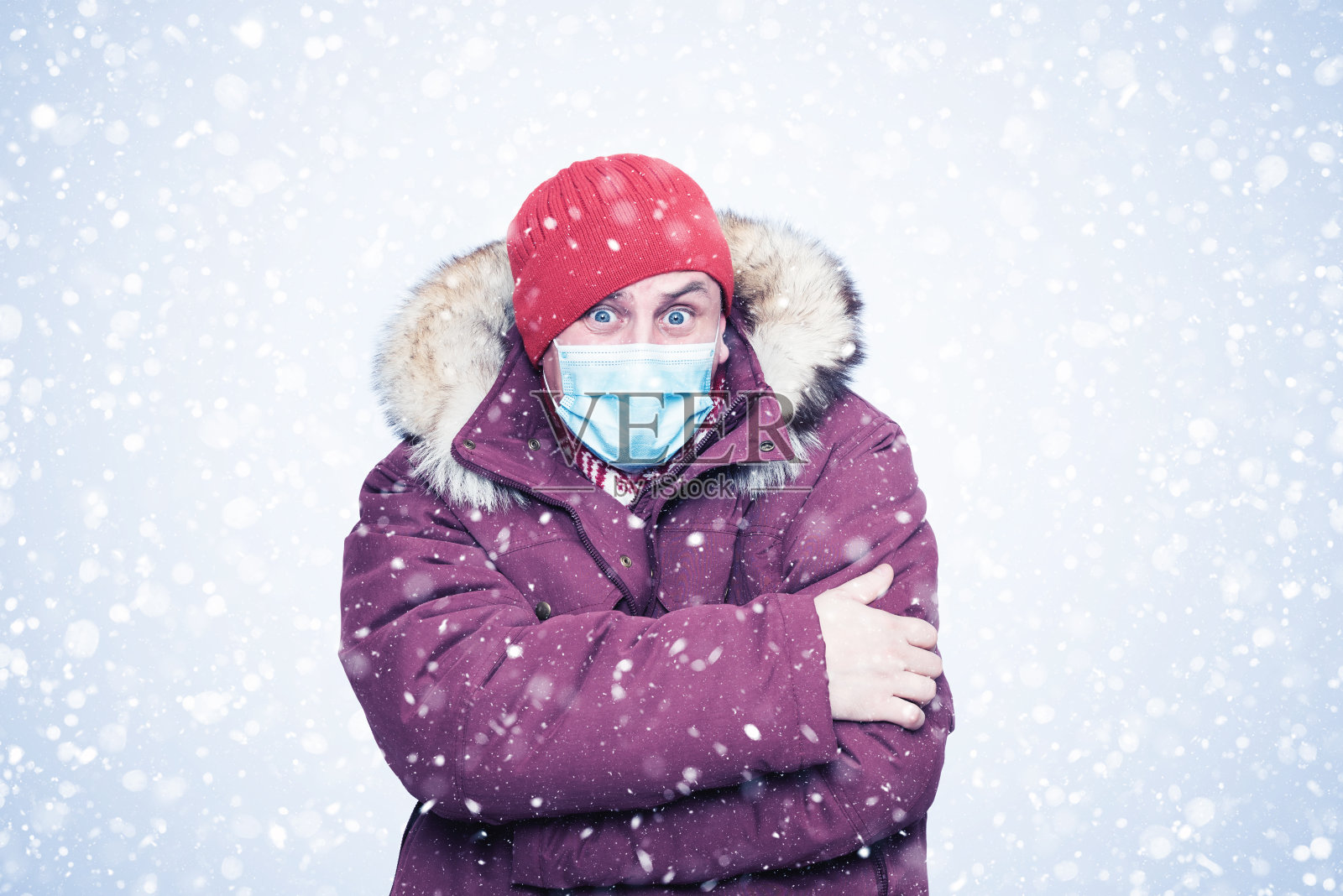 冻人穿着红色的冬衣在脸上戴着防毒面具，以抵御冠状病毒，雪地里到处都是照片摄影图片