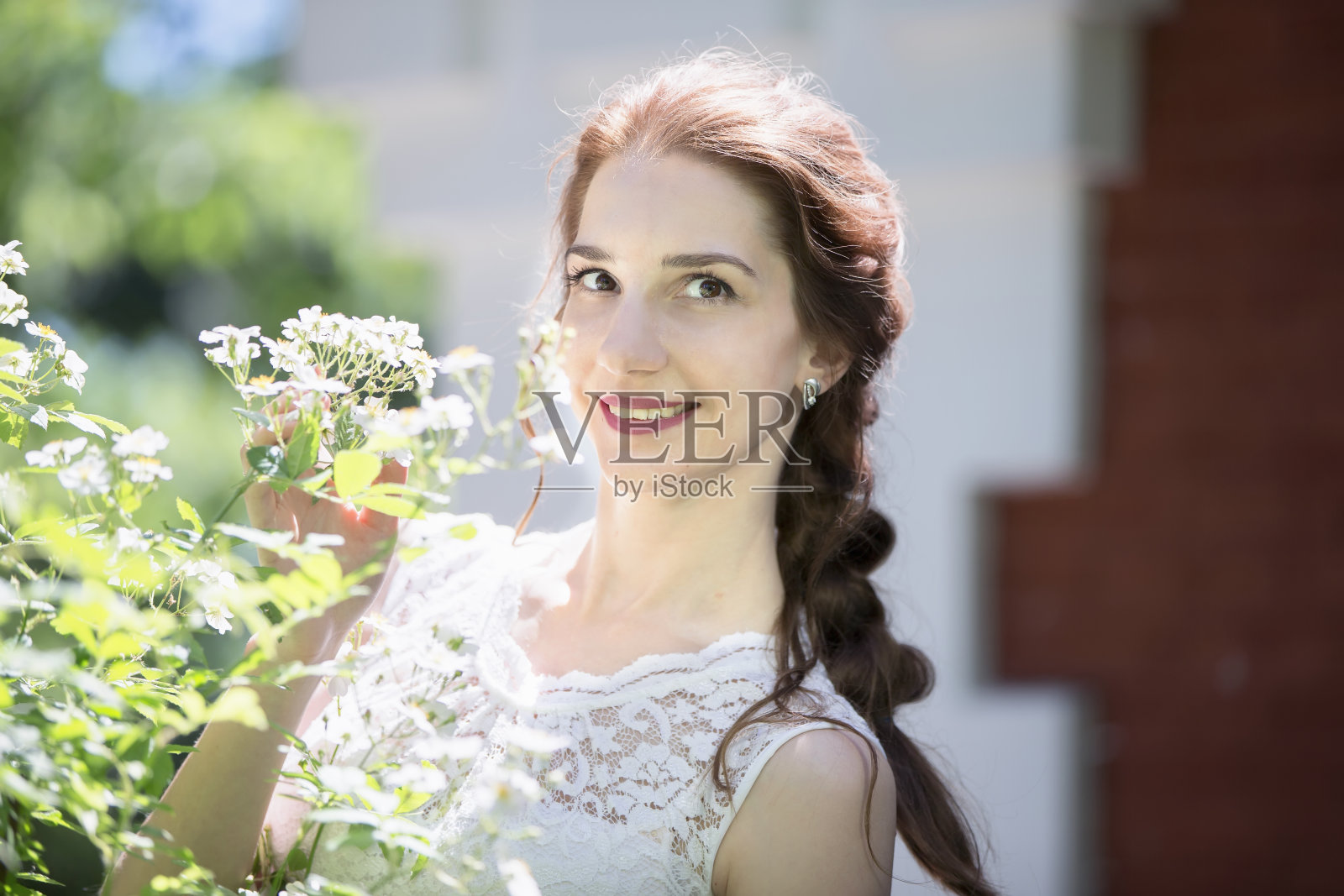 一位手持鲜花的美丽新娘看着镜头微笑。照片摄影图片