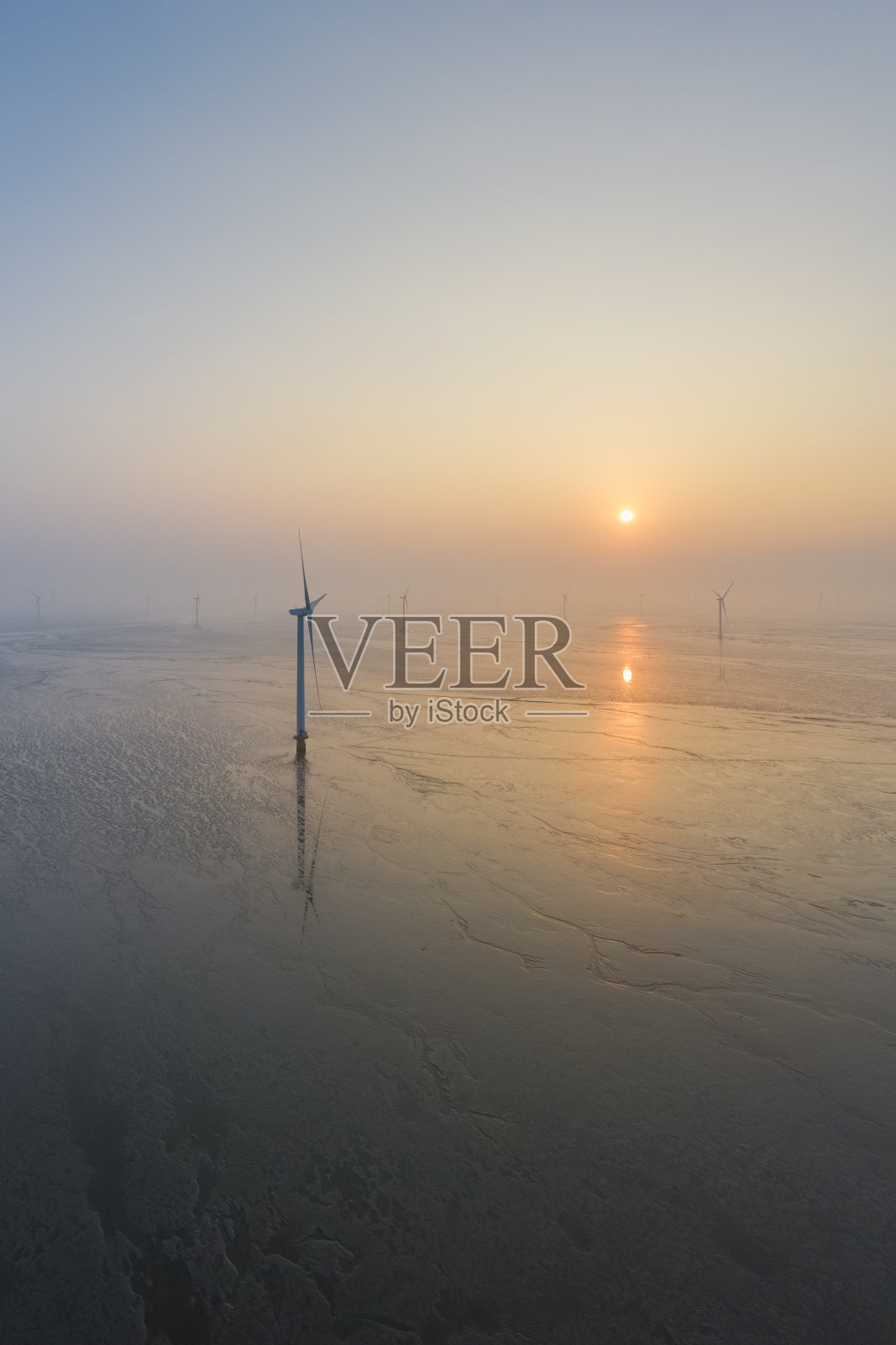 风力发电场在日出的泥滩湿地上照片摄影图片