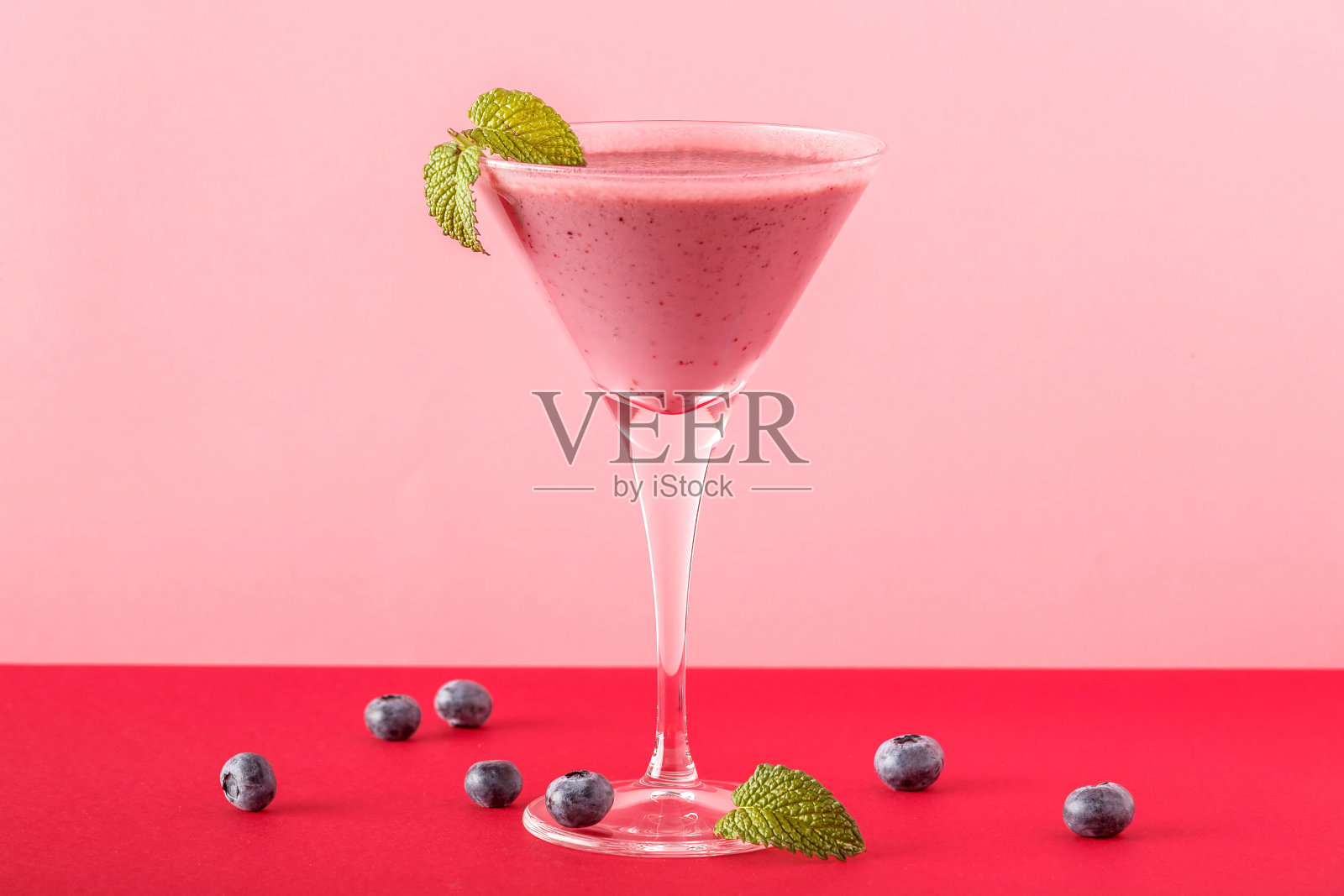 蓝莓冰沙杯与几个蓝莓在一个红色和粉红色的背景。照片摄影图片