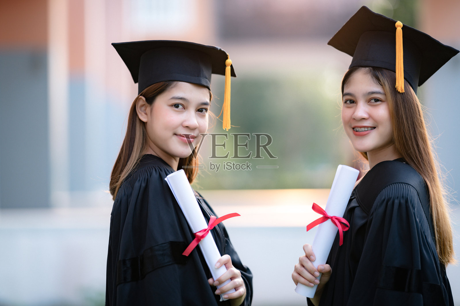 年轻快乐的亚洲女子大学毕业生在毕业礼服和学位证书持有学位证书庆祝教育成就在大学校园。教育库存图片照片摄影图片