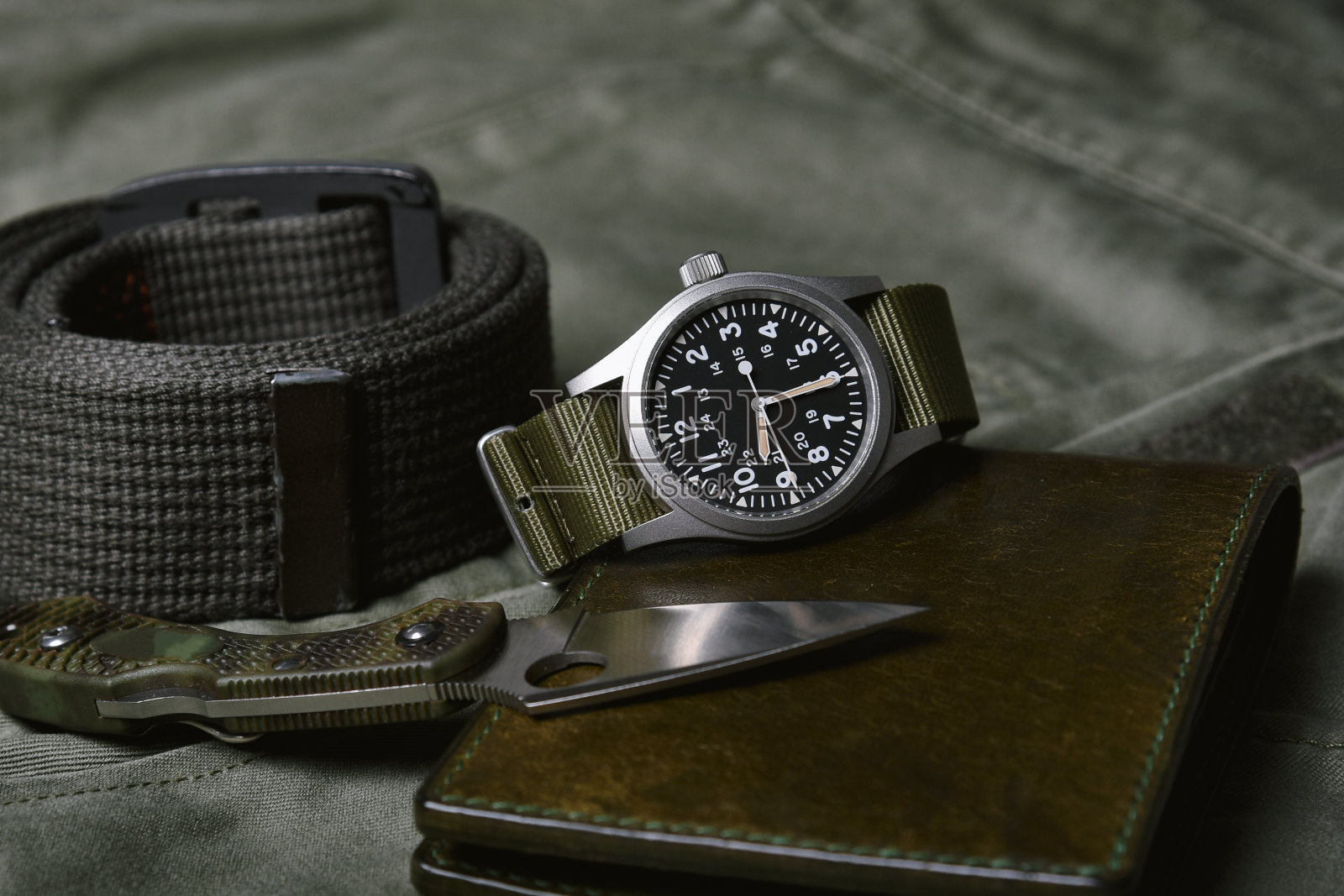 复古军事手表与北约皮带和战术刀在陆军绿色背景，经典的时钟机械手表，军人时尚和配件。照片摄影图片