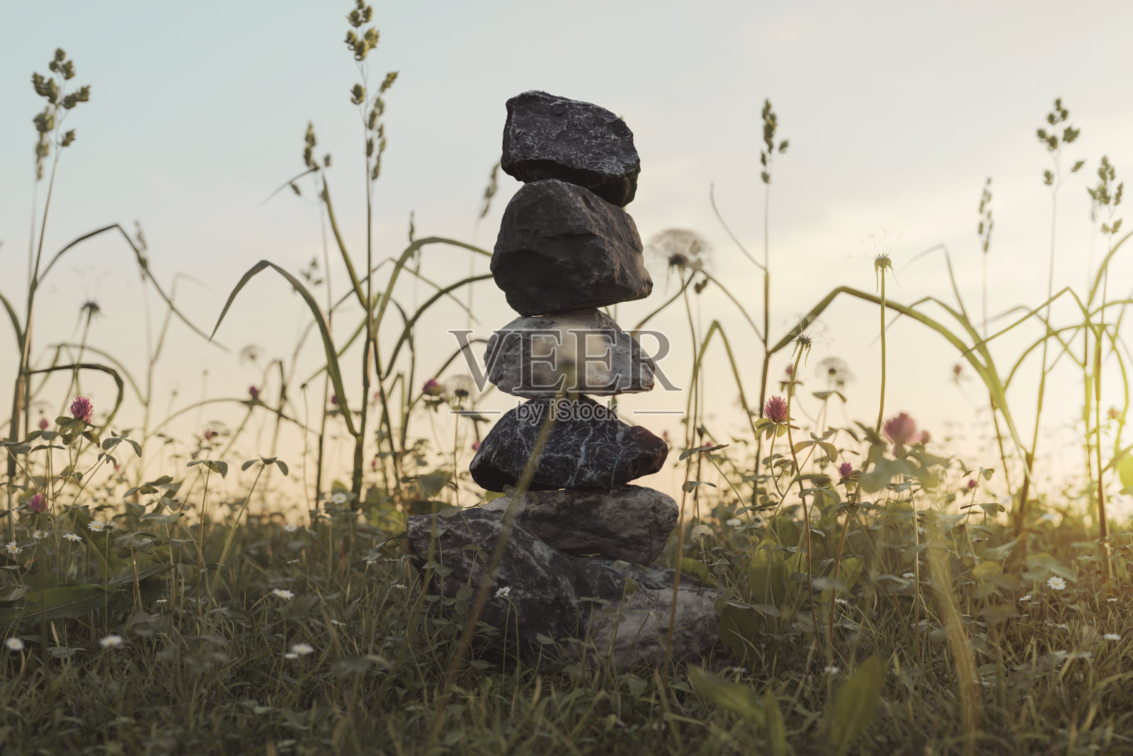 在傍晚阳光下的草地上堆叠的石头的3d渲染照片摄影图片