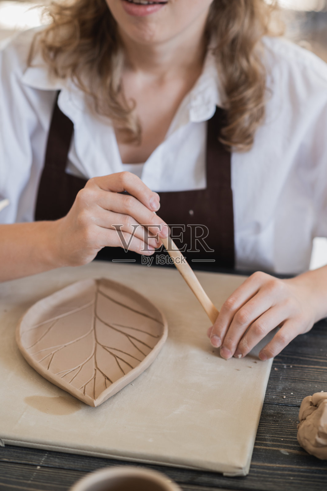 年轻女子在陶艺作坊边雕陶土制品照片摄影图片