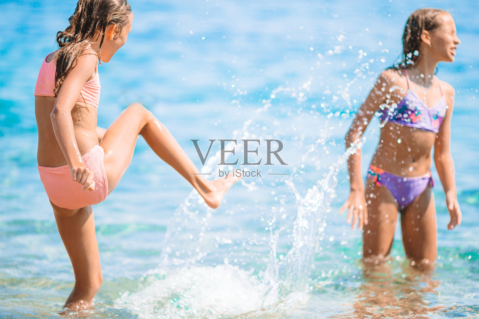 暑假在热带海滩上，快乐的孩子们在海浪中戏水。女孩们在海边玩耍。照片摄影图片