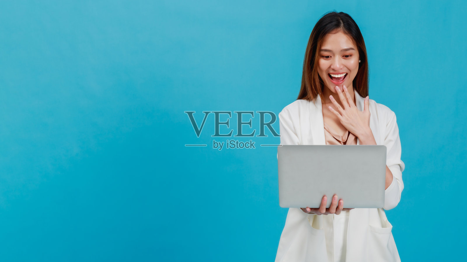 亚洲美丽的商业女性博主使用笔记本电脑和孤立的蓝色背景与复制空间。网上购物与促销的概念。照片摄影图片