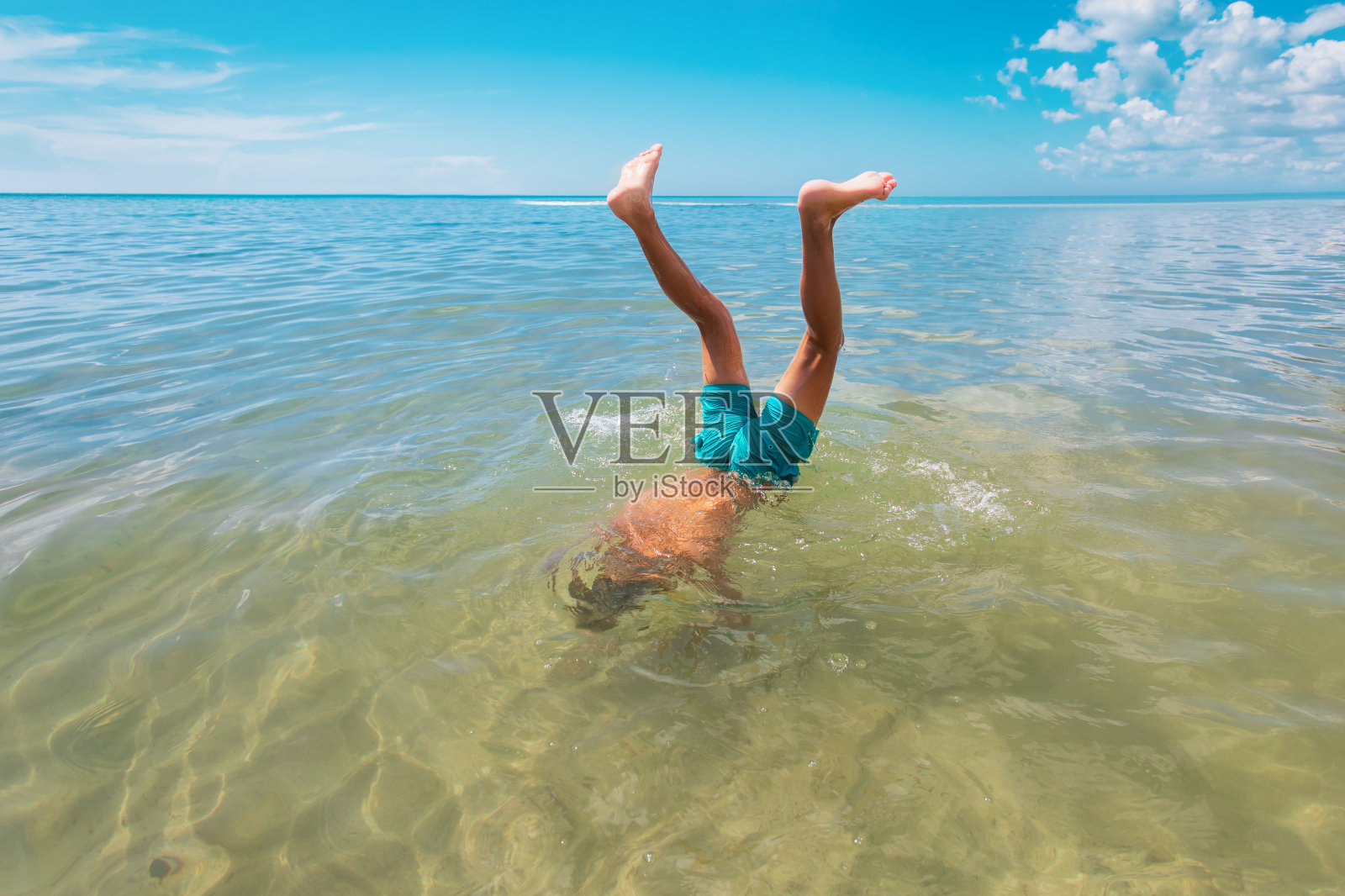 男孩跳入水中，孩子在海里倒立，度假的乐趣照片摄影图片