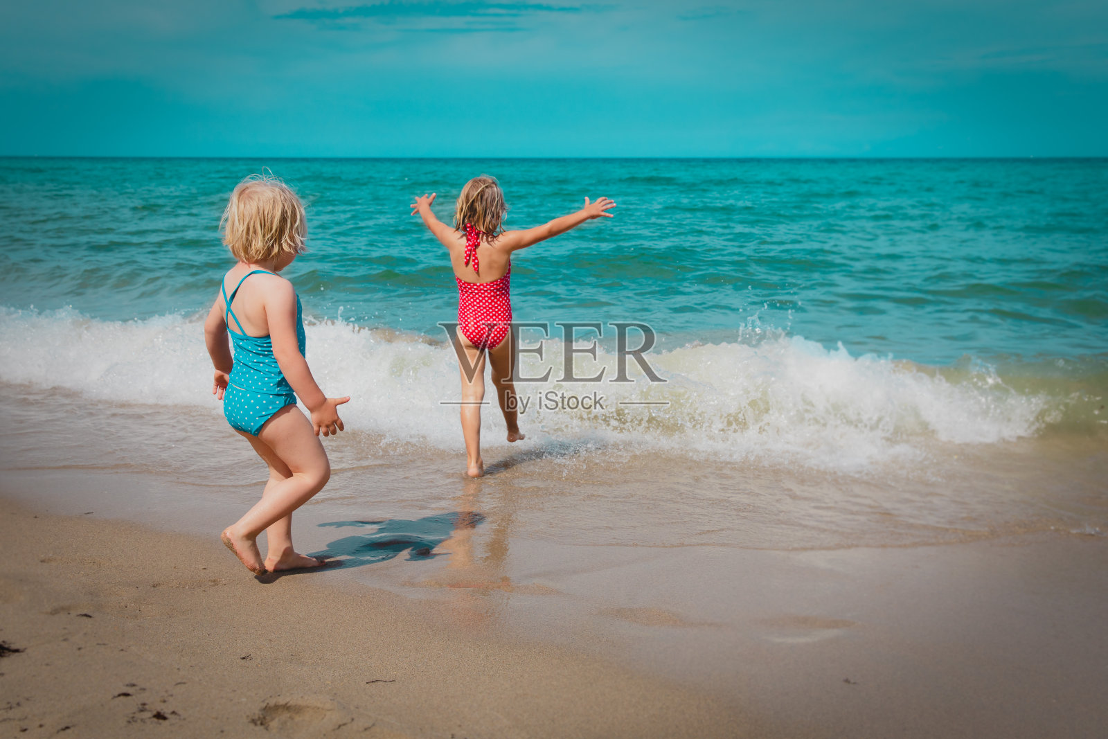 快乐的小女孩们在沙滩上游泳，全家度假照片摄影图片