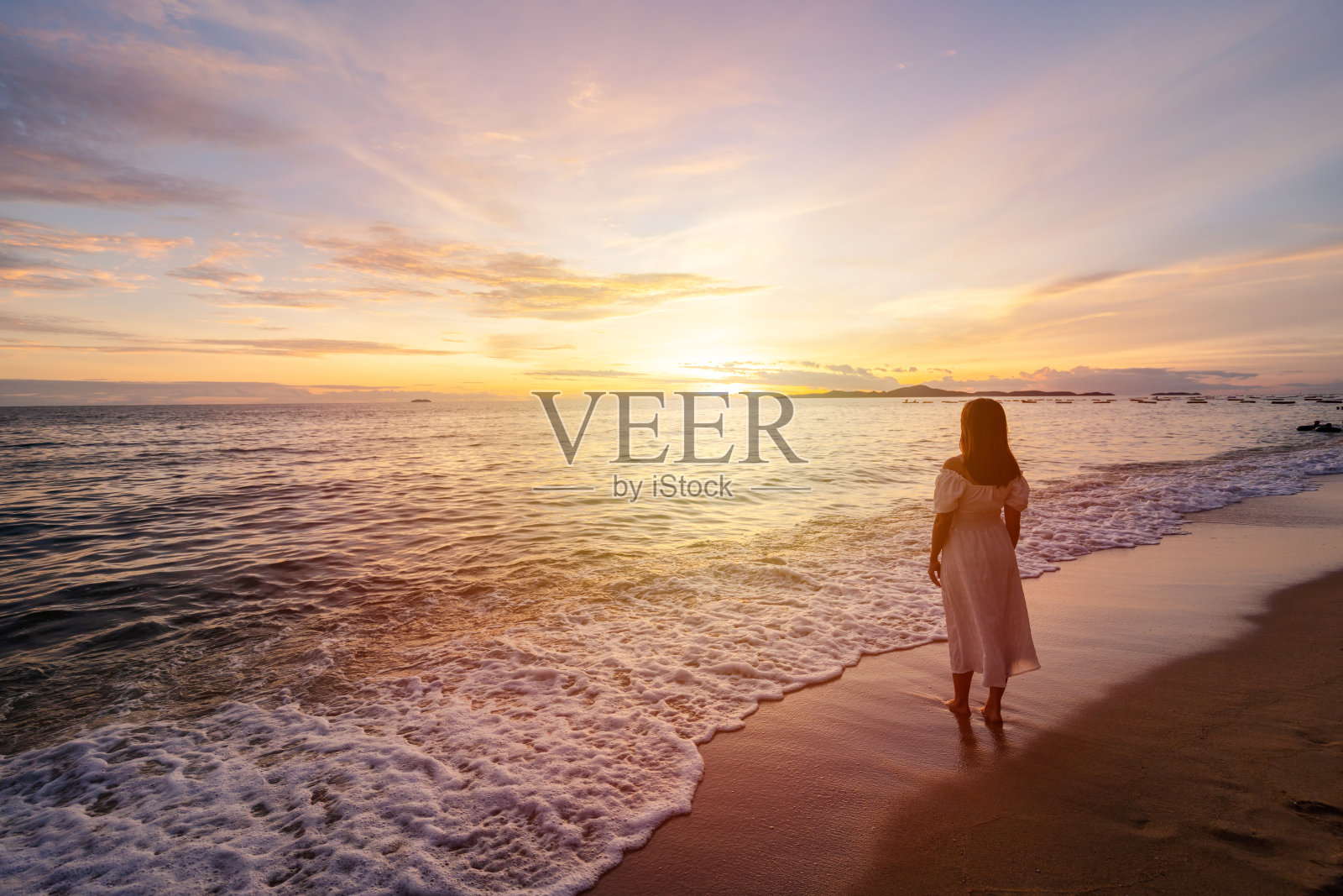 孤独的年轻女子走在宁静的海滩上，享受美丽的日落，在暑假的概念旅行照片摄影图片