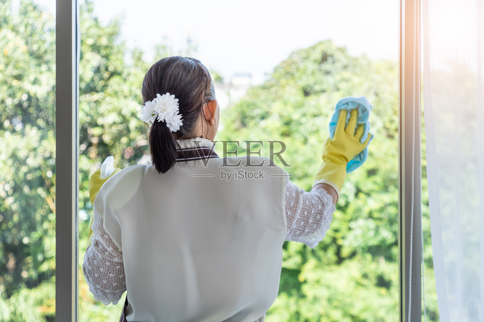 快乐的亚洲资深女性妇女用喷瓶和布清洁窗户玻璃照片摄影图片