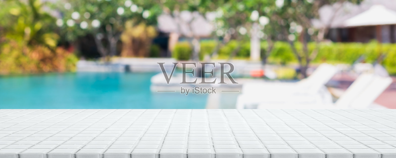 空白色陶瓷马赛克桌面和模糊的游泳池在热带度假夏季横幅背景-可以用来展示或蒙太奇您的产品。照片摄影图片