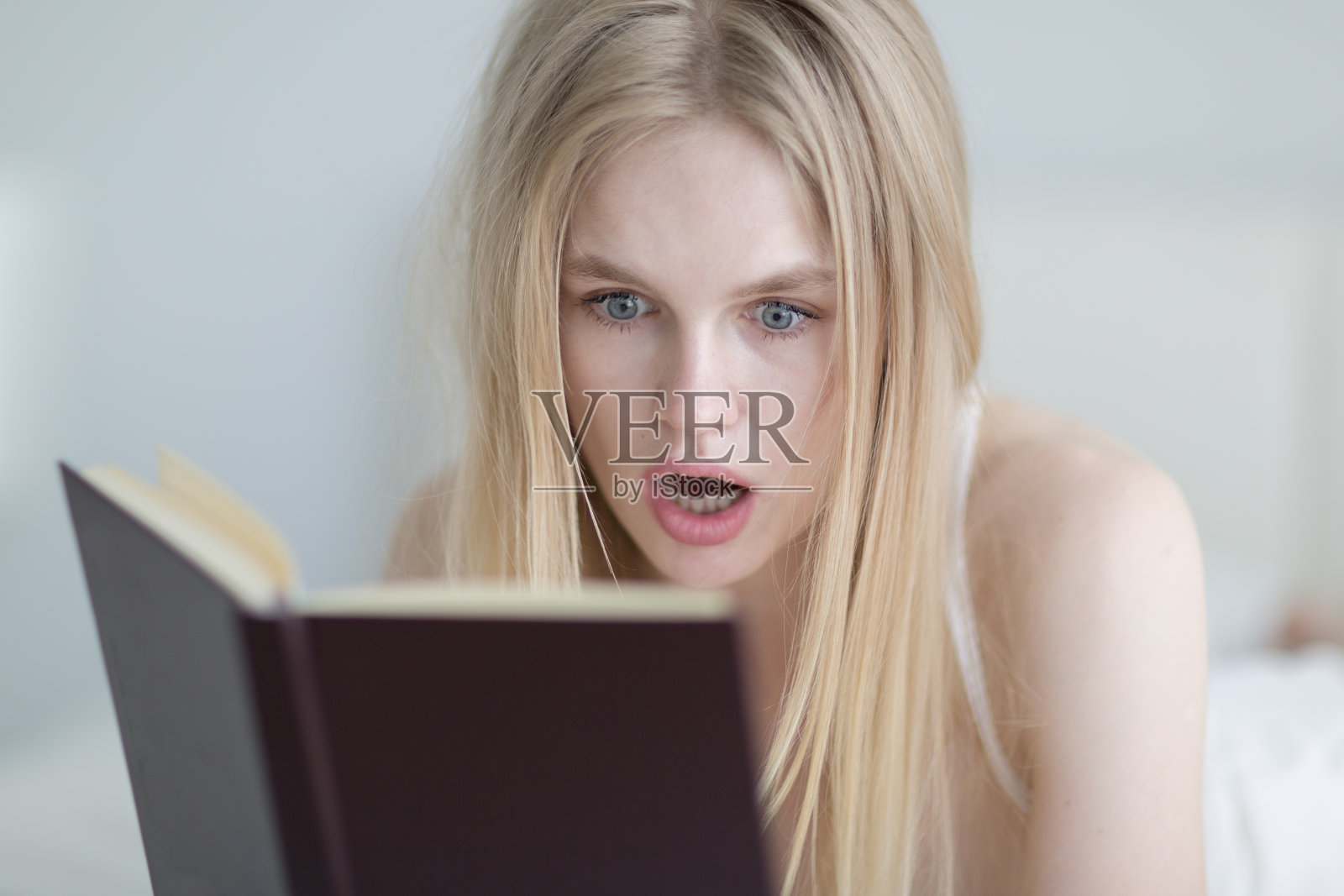 专心读书的年轻女子看上去很惊讶。文学和教育。照片摄影图片