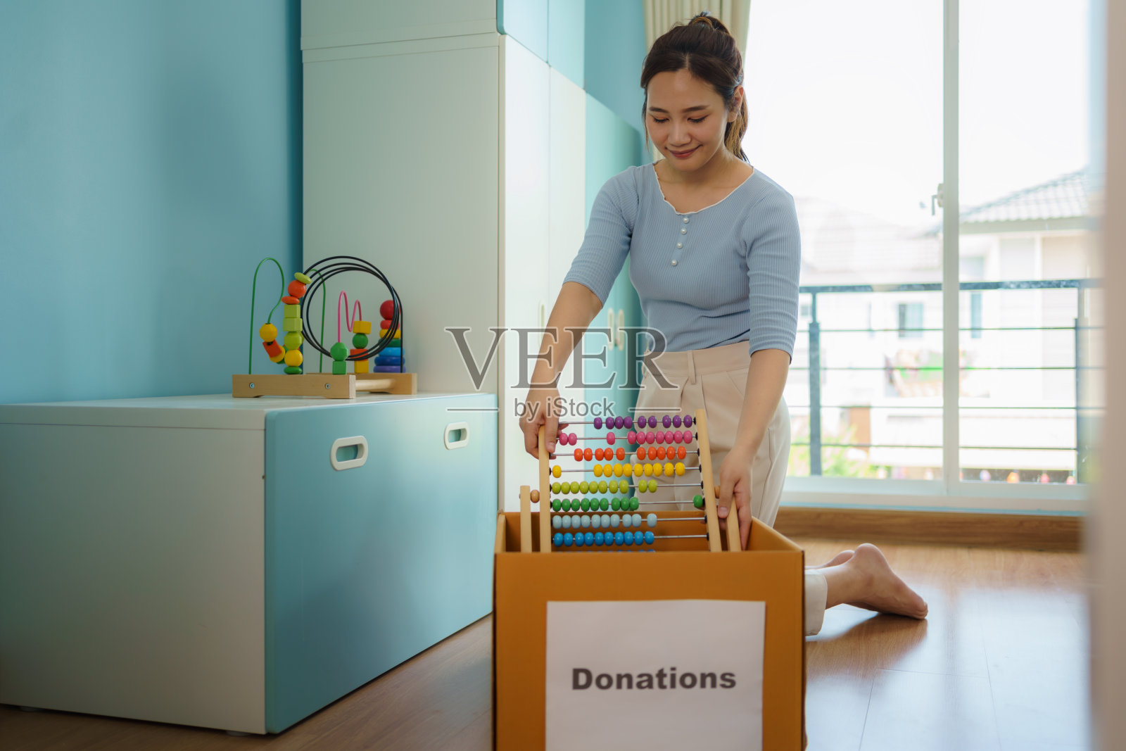 亚洲母亲正在为孩子挑选不能玩的玩具，并把捐款箱送到捐赠中心。照片摄影图片