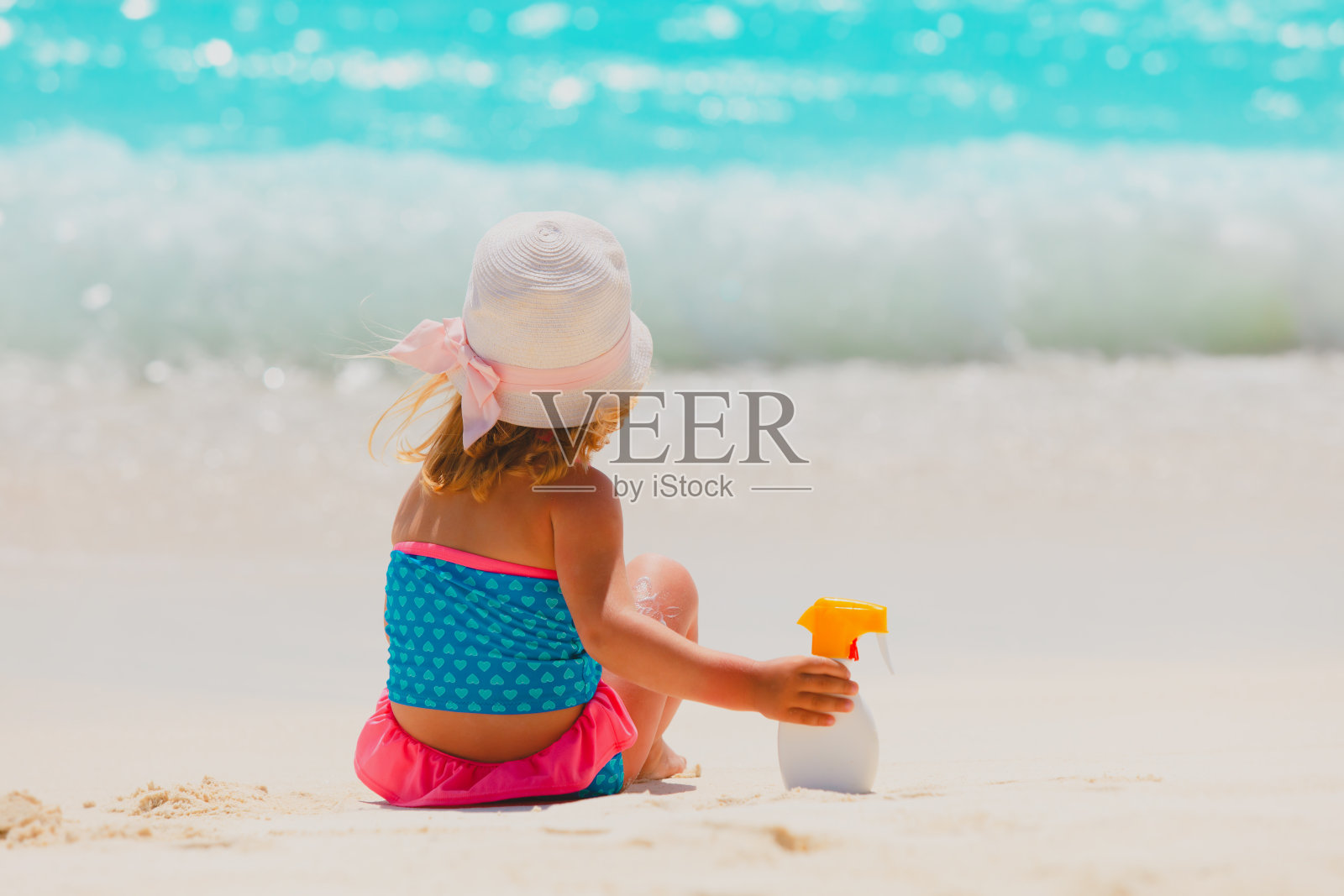 在热带海滩上涂着防晒霜的小女孩照片摄影图片