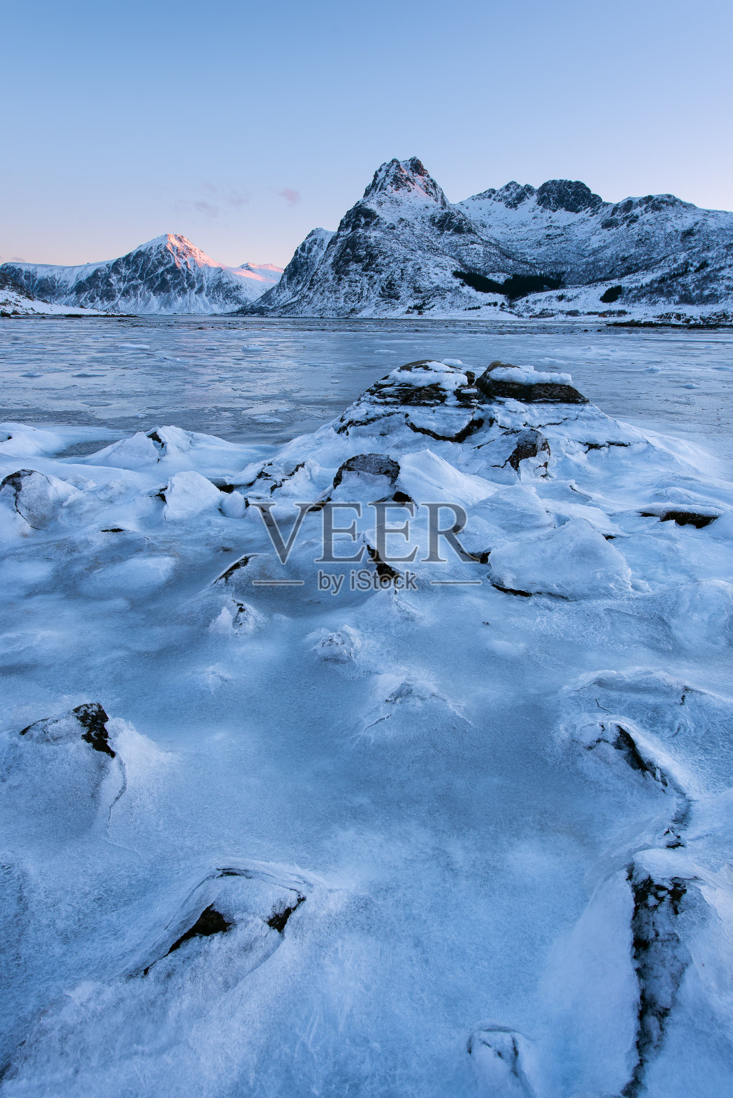 挪威罗浮敦群岛，美丽的景观开裂的冰，冰冻的海岸与山脉背景在冬季日落照片摄影图片