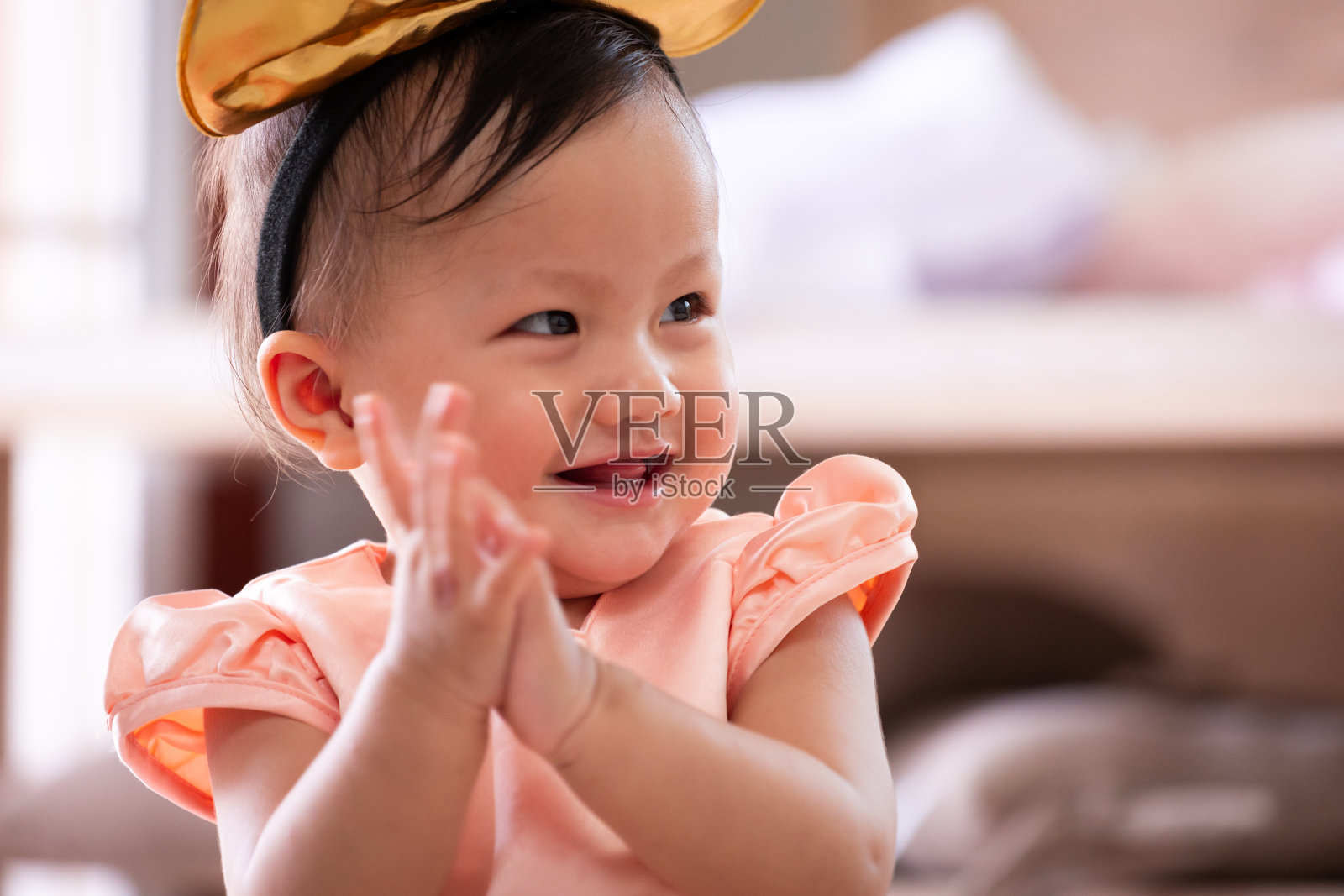 可爱的亚洲小女孩微笑着拍拍手，与她的父母在客厅玩。照片摄影图片
