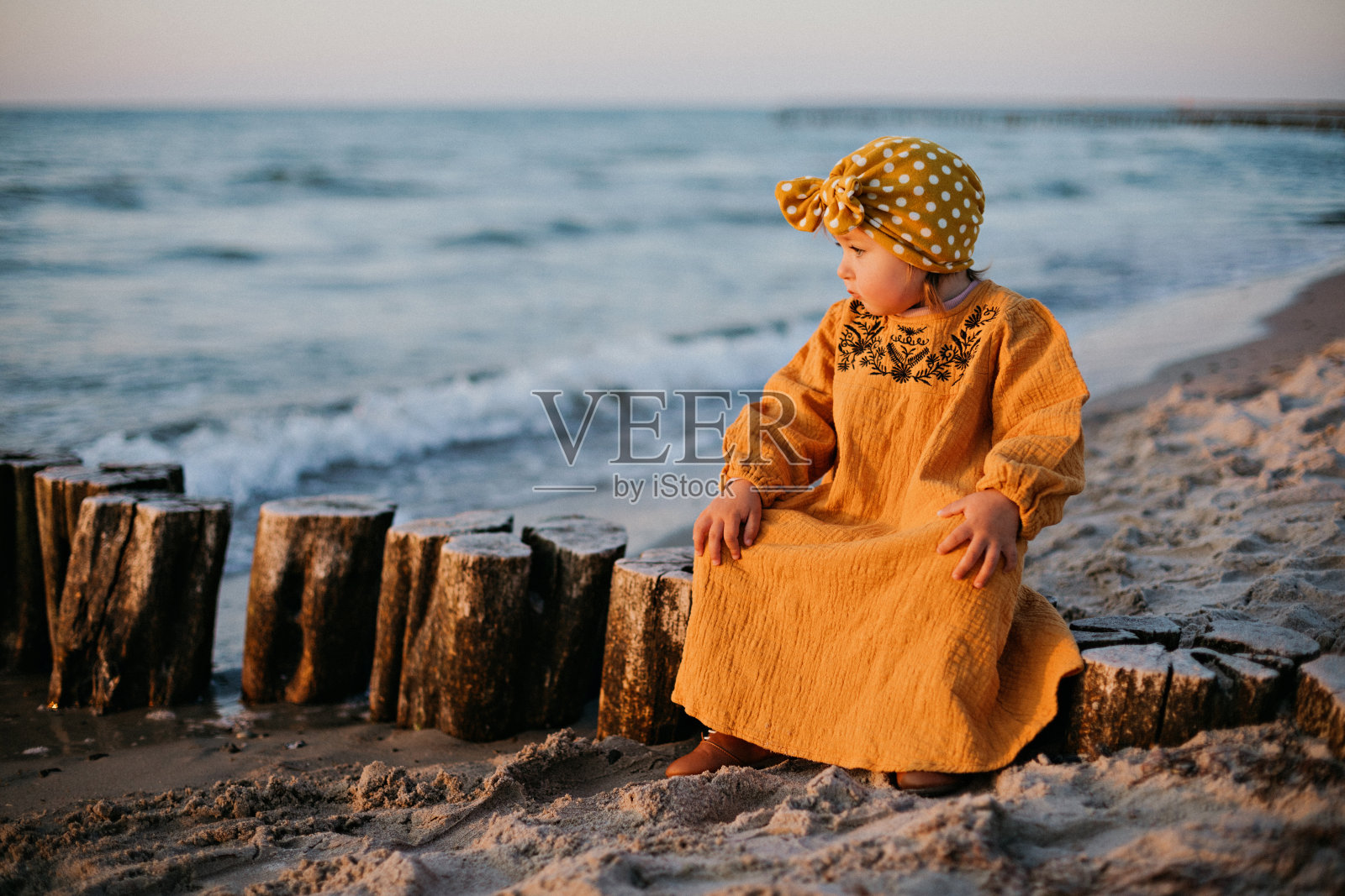 美丽的孩子坐在波罗的海的防波堤上照片摄影图片