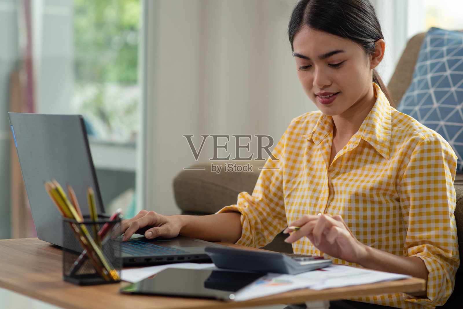 年轻的亚洲女商人在她的家里用笔记本电脑工作，在家工作，商业概念照片摄影图片
