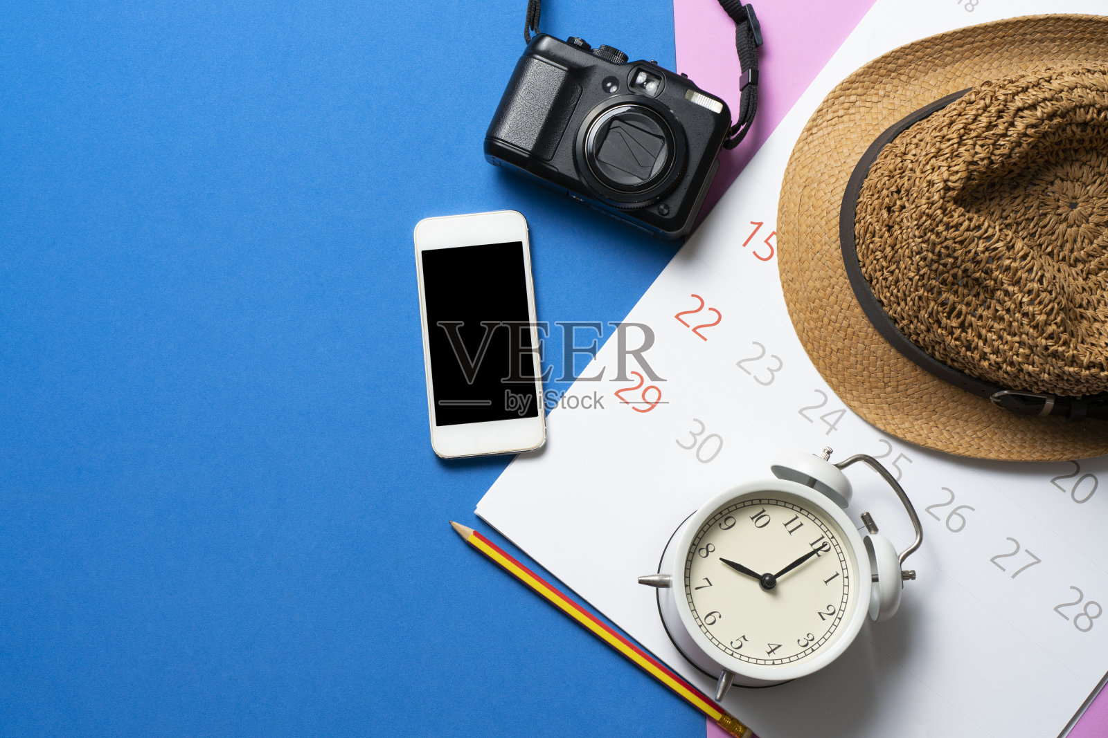 近距离的日历，手机，相机，闹钟和帽子上的蓝色和粉红色的桌子背景，旅行计划的概念照片摄影图片