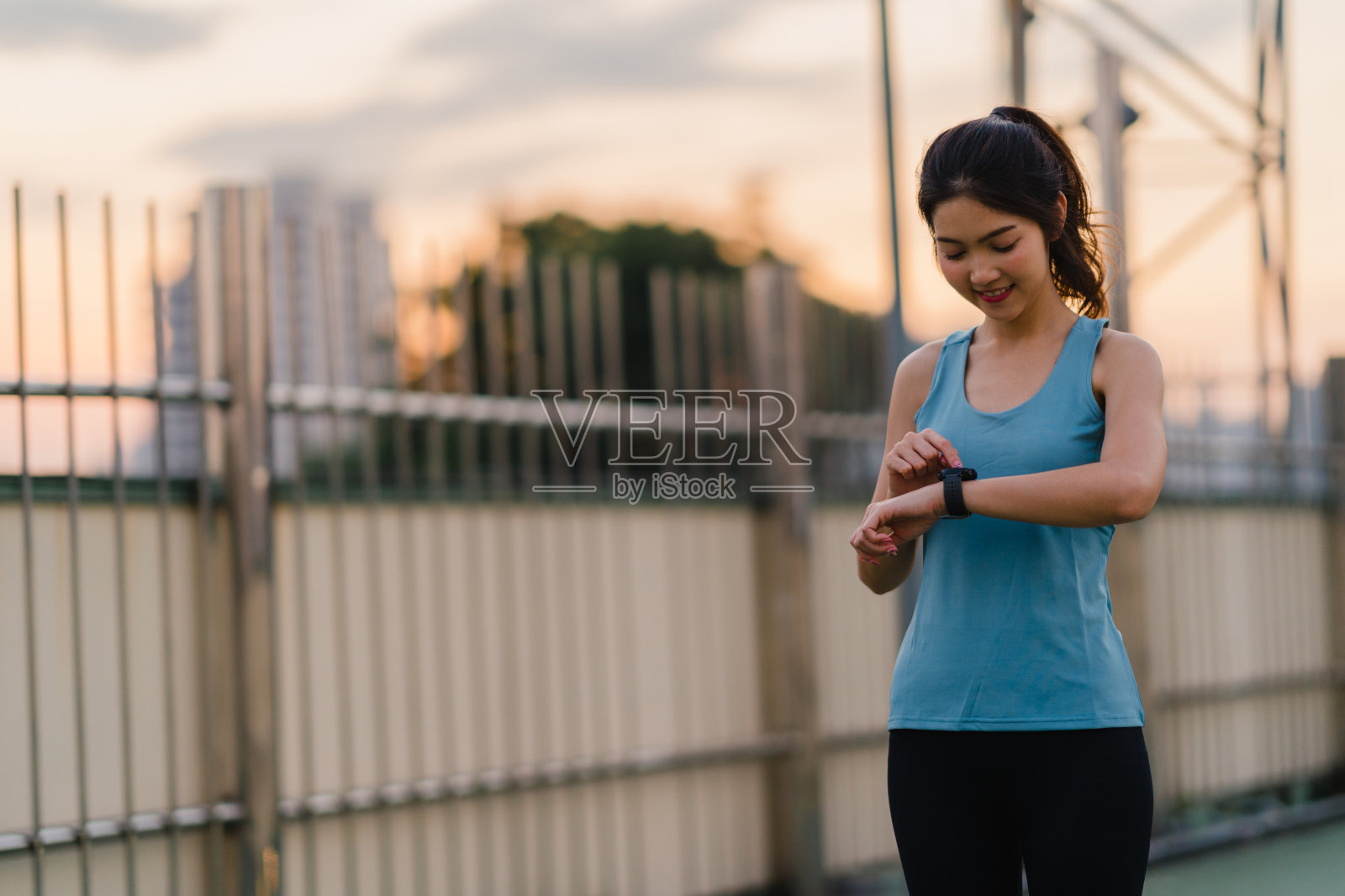 美丽年轻的亚洲运动员女士在城市环境做伸展运动。日本少女穿着运动服在天桥上在清晨。生活方式积极的运动在城市。照片摄影图片