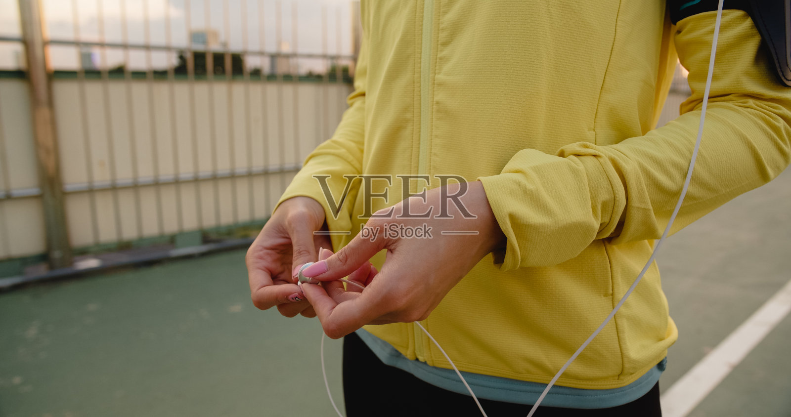 美丽年轻的亚洲女运动员练习使用智能手机听音乐，同时在城市环境中跑步。照片摄影图片
