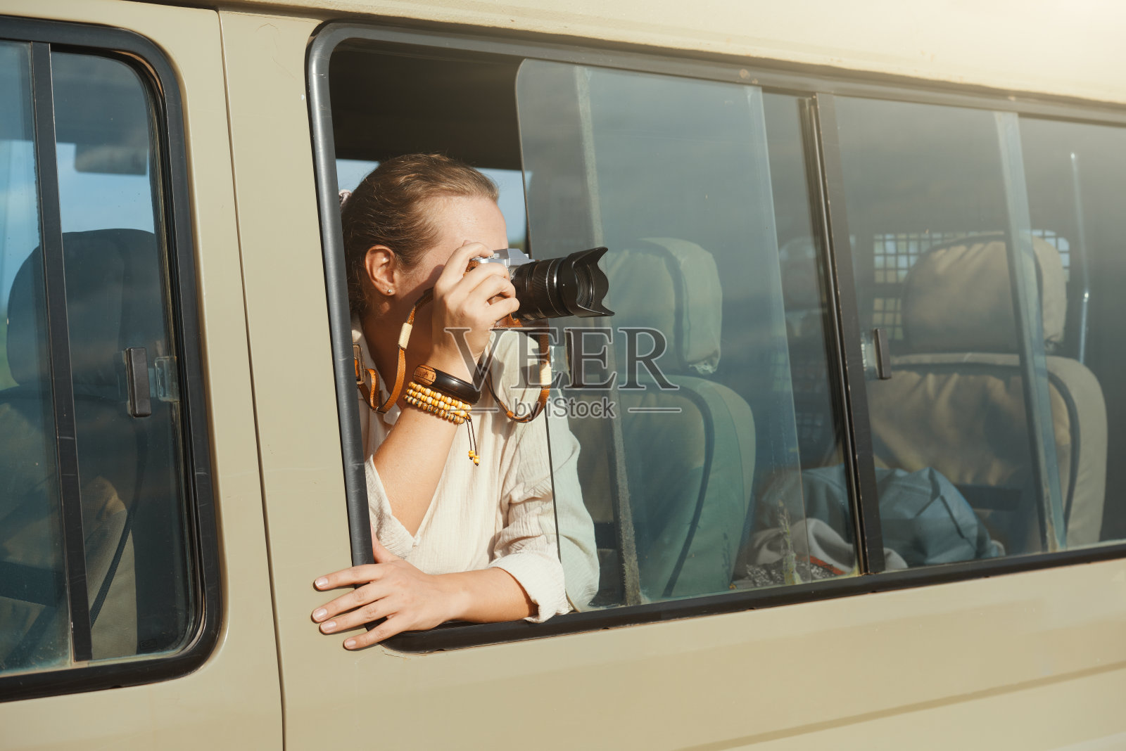 在一个阳光明媚的日子里，一个女人在车里拿着相机照片摄影图片