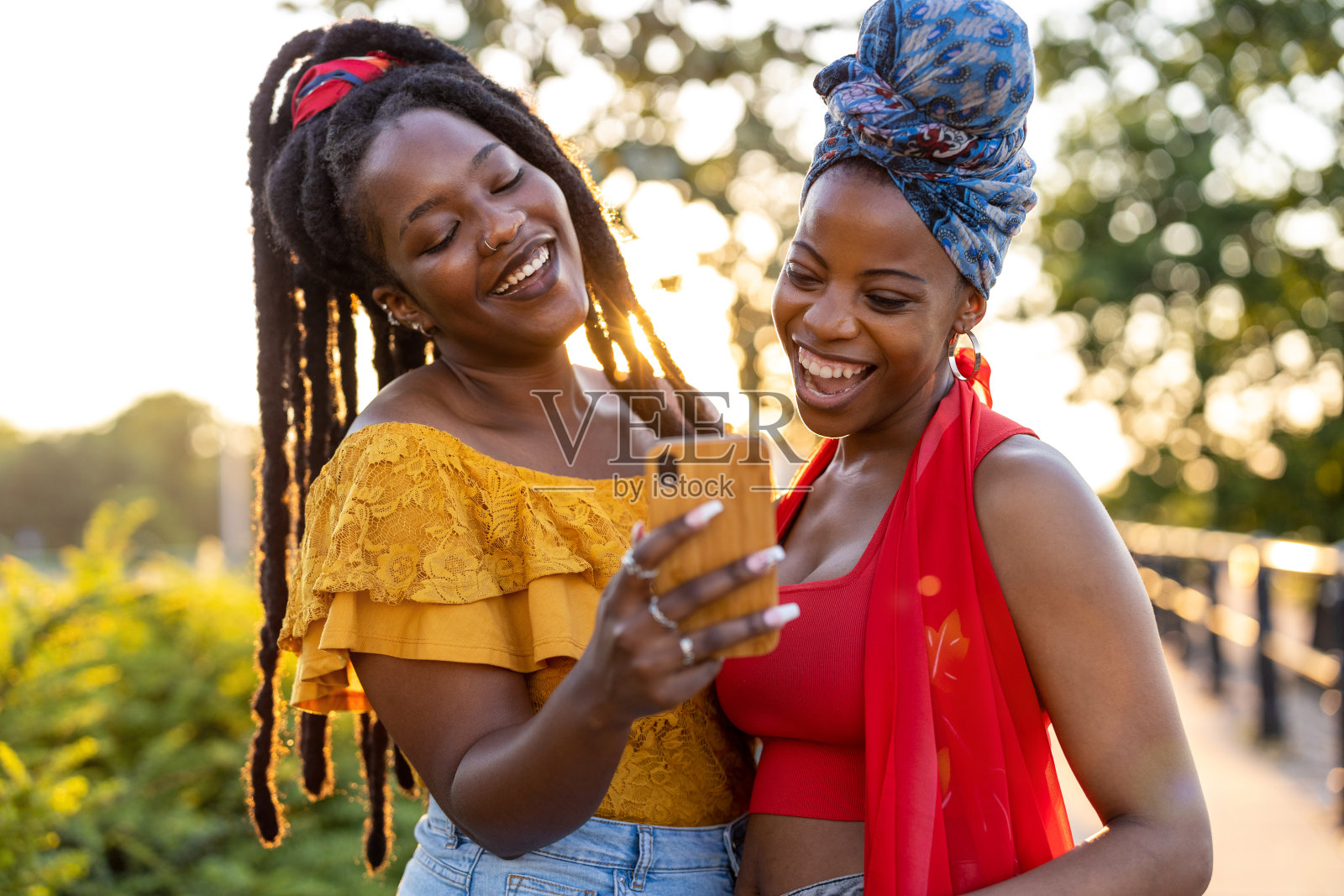 两个女性朋友拿着智能手机，在户外微笑照片摄影图片