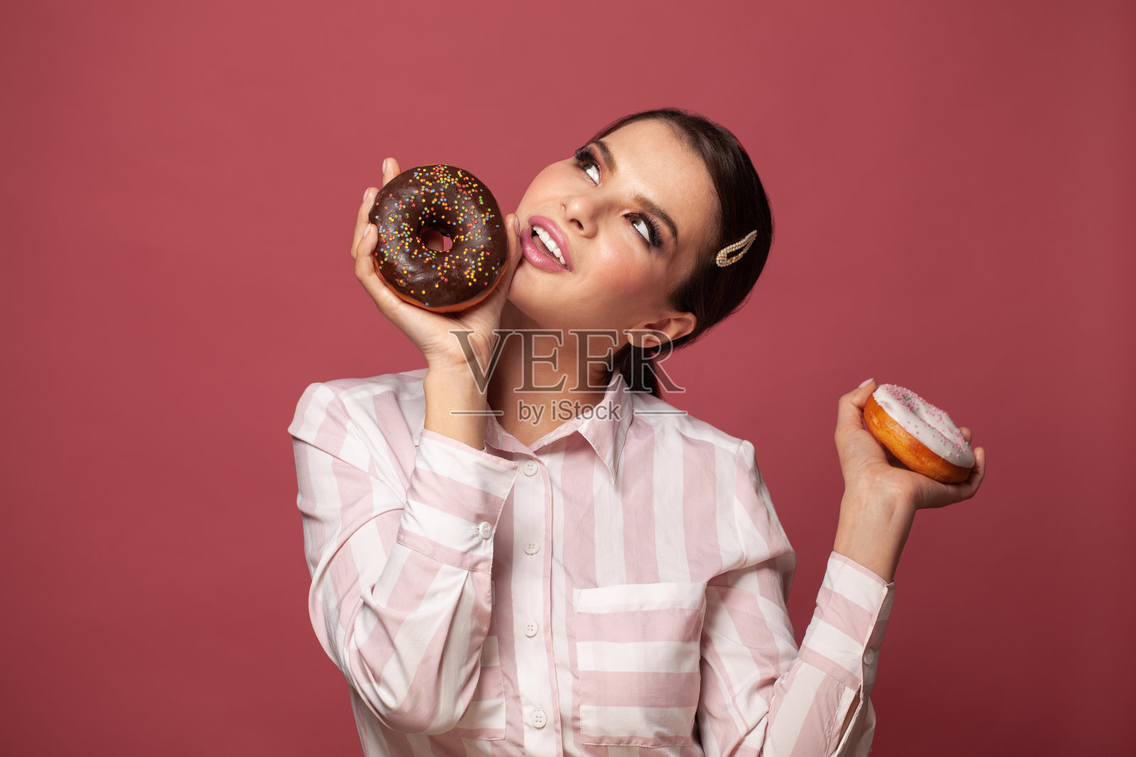 快乐乐观的年轻女子吃甜甜圈糖果的照片在红色的背景照片摄影图片