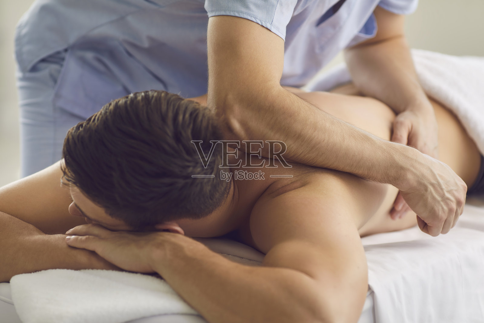 男子在接受康复治疗期间享受专业按摩师的身体按摩照片摄影图片